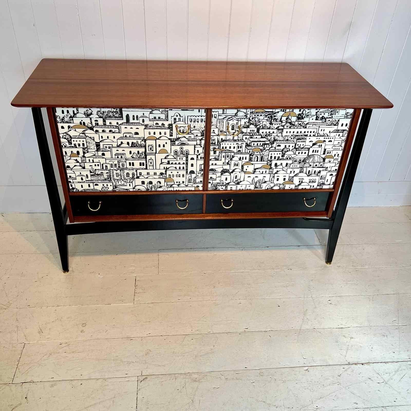 A beautifully made teak sideboard from the 1950's. Creatively decoupaged with a paper that featured in Piero Fornasetti’s Milan residence. The sideboard has been restored, stripped, sanded and oiled by hand. A wonderfully figured top sits above two
