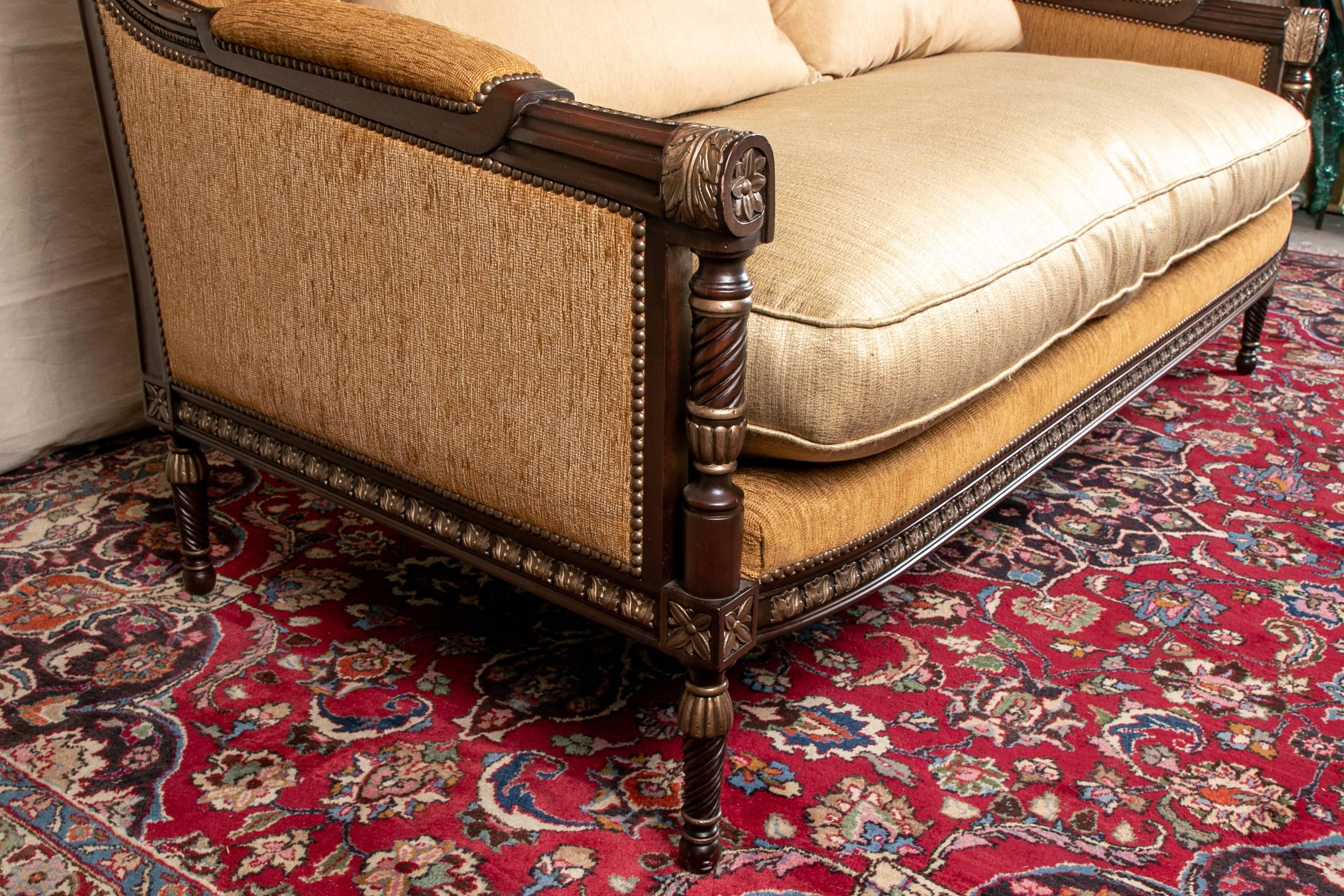 Berber Kamlah collection for CHB, carved and gilt mahogany frame with turned arms and legs, a leafy frieze on the lower frame, and a large gilt bow and leaf crest rail finial, upholstered in a tan textured fabric with nail heads, the cushions in a