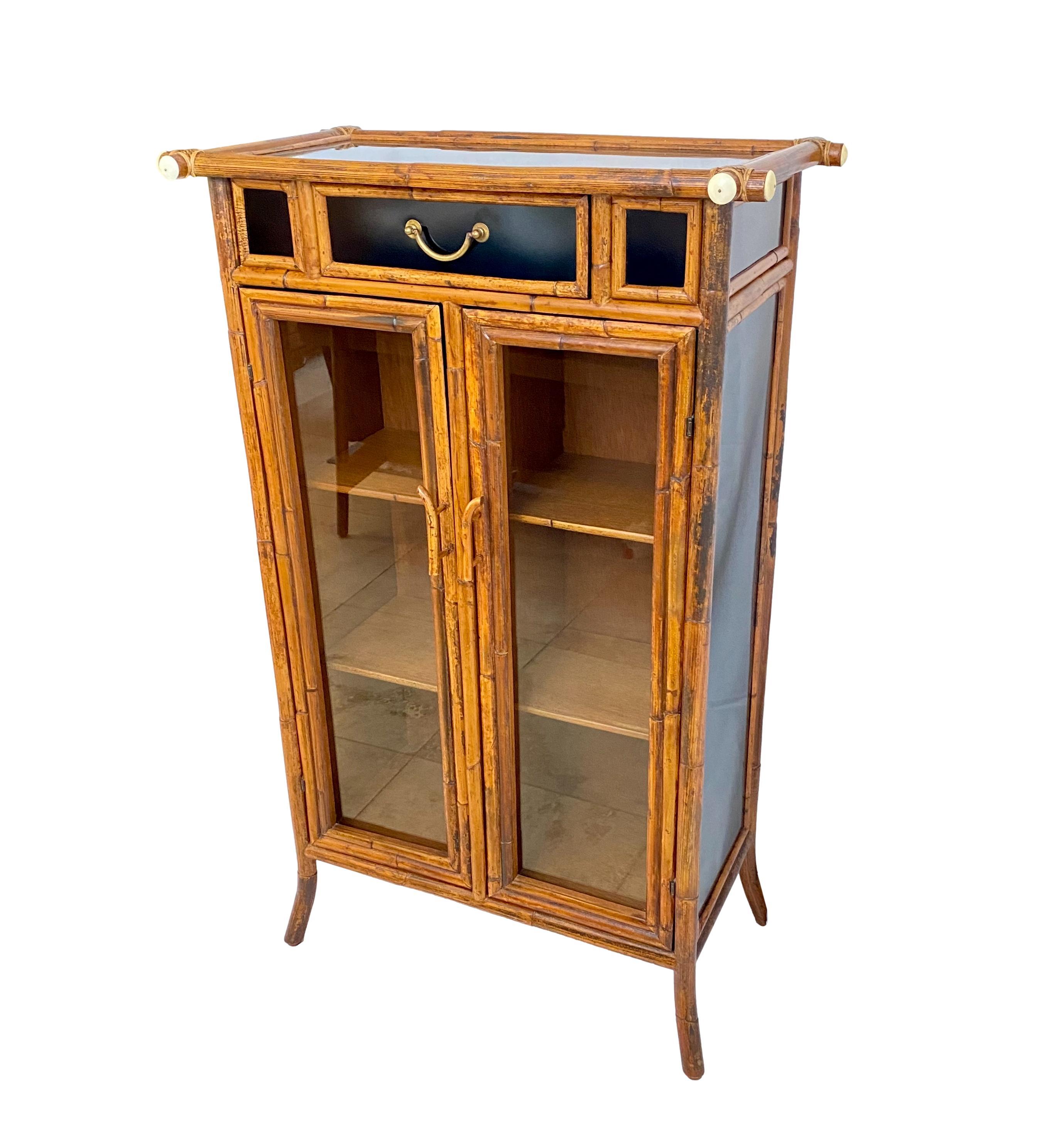 An aesthetic movement style scorched rattan and black lacquer bookcase or display cabinet by E. Murio (Manila) c. 2010. It features bone button caps, a single drawer with brass handle, a two-door cabinet with inset glass panels, four removable wood