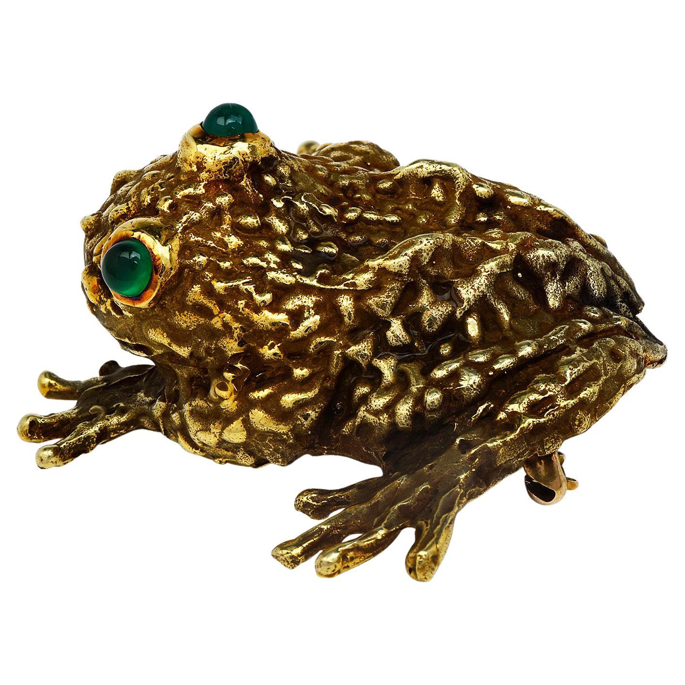 A peculiar Toad brooch pin by E. Pearl company , highly collectible with a textured finish, 

This vintage brooch pin is crafted in 69.1 grams of 18K yellow gold. 

The eyes of the frog are  2 Cabochon round cut Emeralds, bezel-set, 

weighing appx.