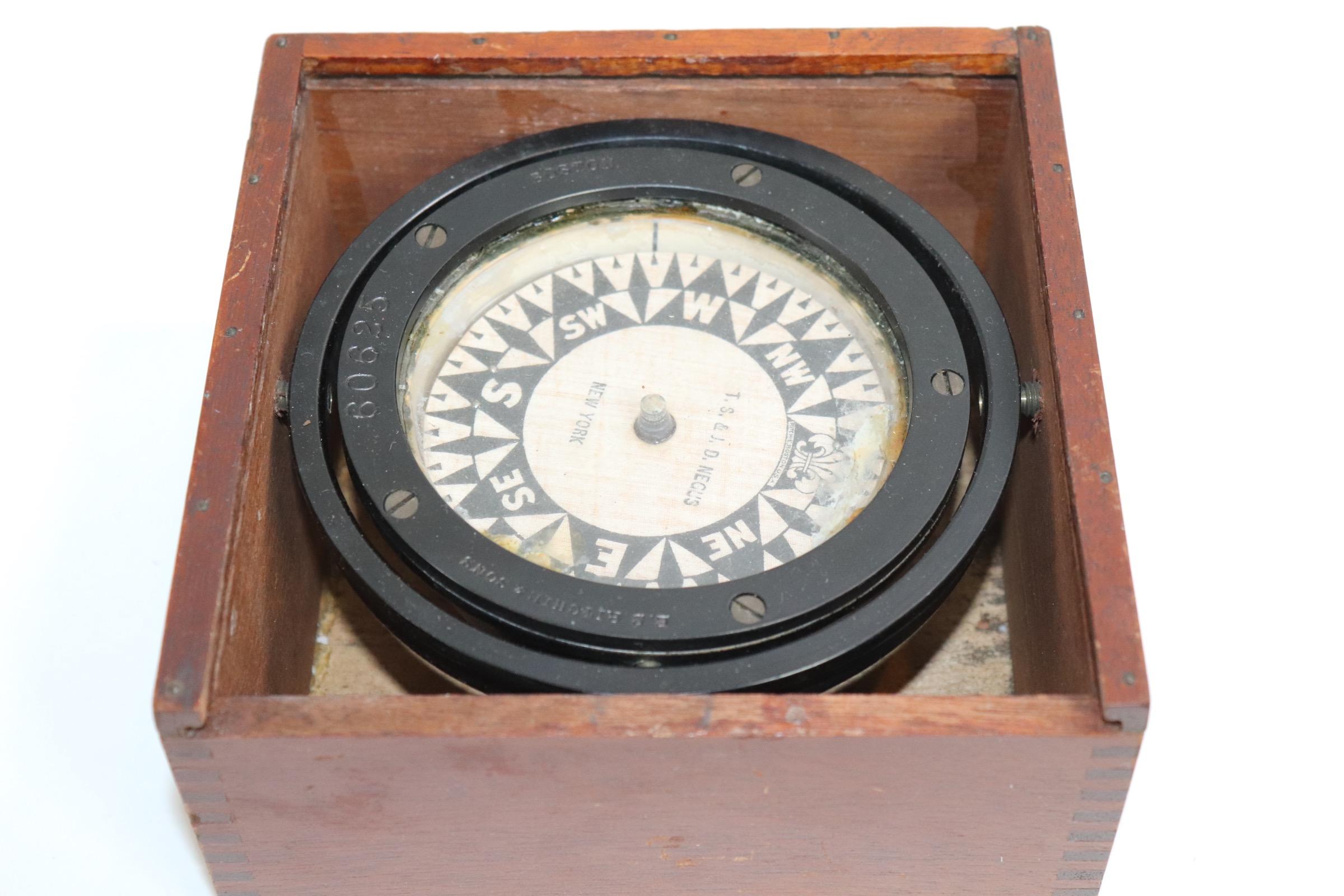 Boxed boat compass by E.S.Ritchie and sold by T.S. and J.D. Negus. Serial number 80625. Compass is painted black and is set into a varnished wood box with sliding lid. Weight is 4 pounds.