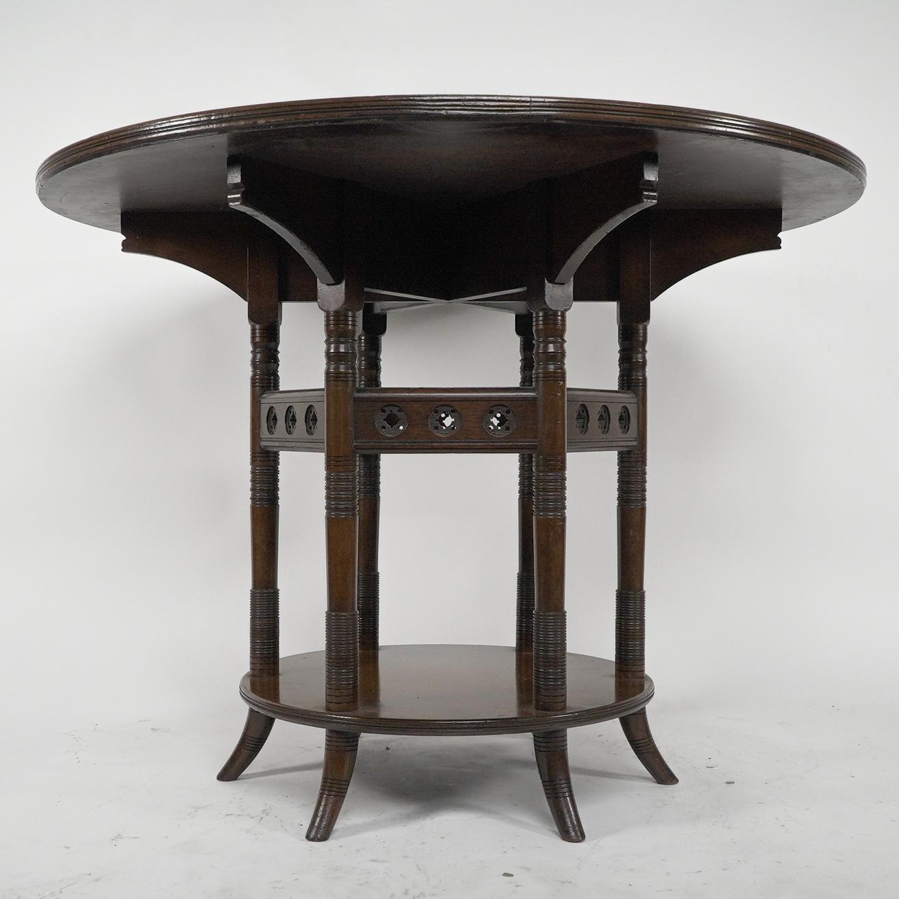 E W Godwin attributed. Made by Collinson & Lock. An Aesthetic Movement six leg walnut circular centre table with shaped radiating under supports and subtle shaped details to the ends. Stood on finely turned legs united by six upper surrounding