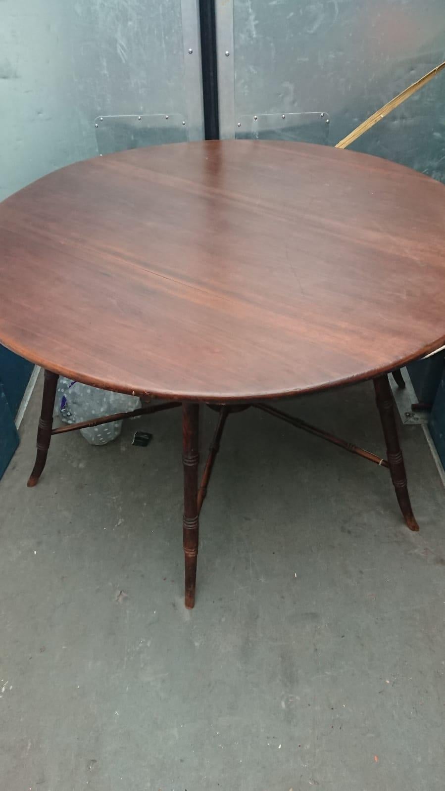 E W Godwin, attributed. Probably made by Collinson and Lock. 
An Anglo-Japanese Aesthetic Movement walnut centre or dining table, with a large circular top with a shaped apron below, on six flaring turned legs, united by six radiating spoke