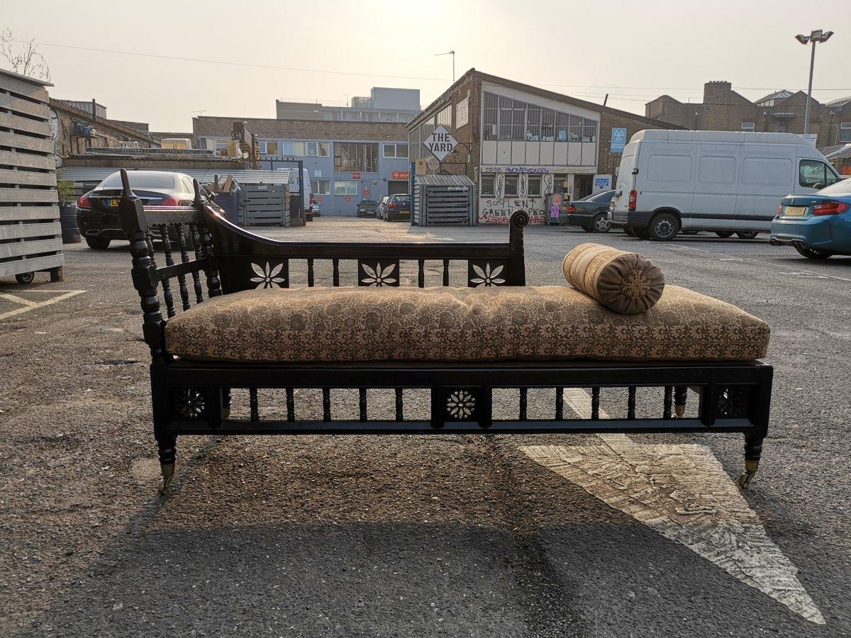 In the style of E W Godwin. Anglo-Japanese / Aesthetic Movement ebonized chaise lounge.
With turned finials and turned uprights flanked by stylized floral fretwork devises to the back rest and to the apron below. On ball turned legs with the