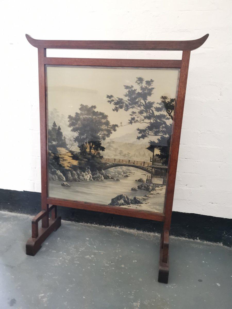 Edward William Godwin, attributed. An Anglo Japanese Mahogany fire screen with the original Japanese silk depicting a bridge over a river in a country scene.
