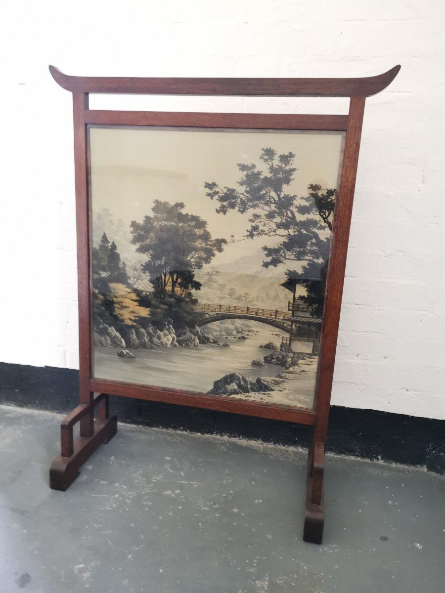 Edward William Godwin, zugeschrieben. Ein anglo-japanischer Mahagoni-Kaminschirm mit der originalen japanischen Seide, die eine Brücke über einen Fluss in einer ländlichen Szene darstellt.
