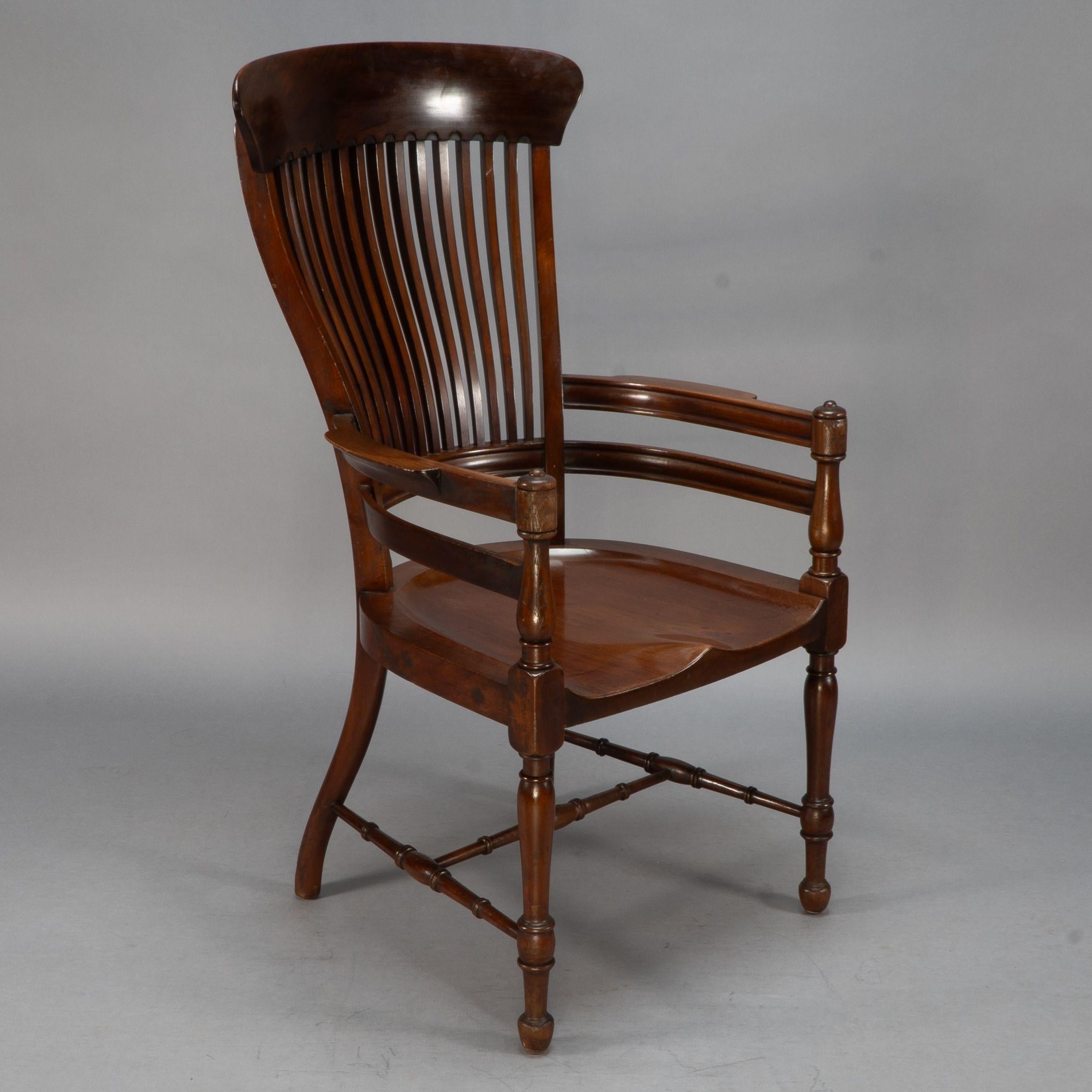E. W. Godwin (attributed) Made by James Peddle or Smee. A tall back serpentine shape walnut armchair with an ergonomically perfectly shaped slatted back with curved arms and a shaped seat and turned H stretcher below. A very comfortable armchair