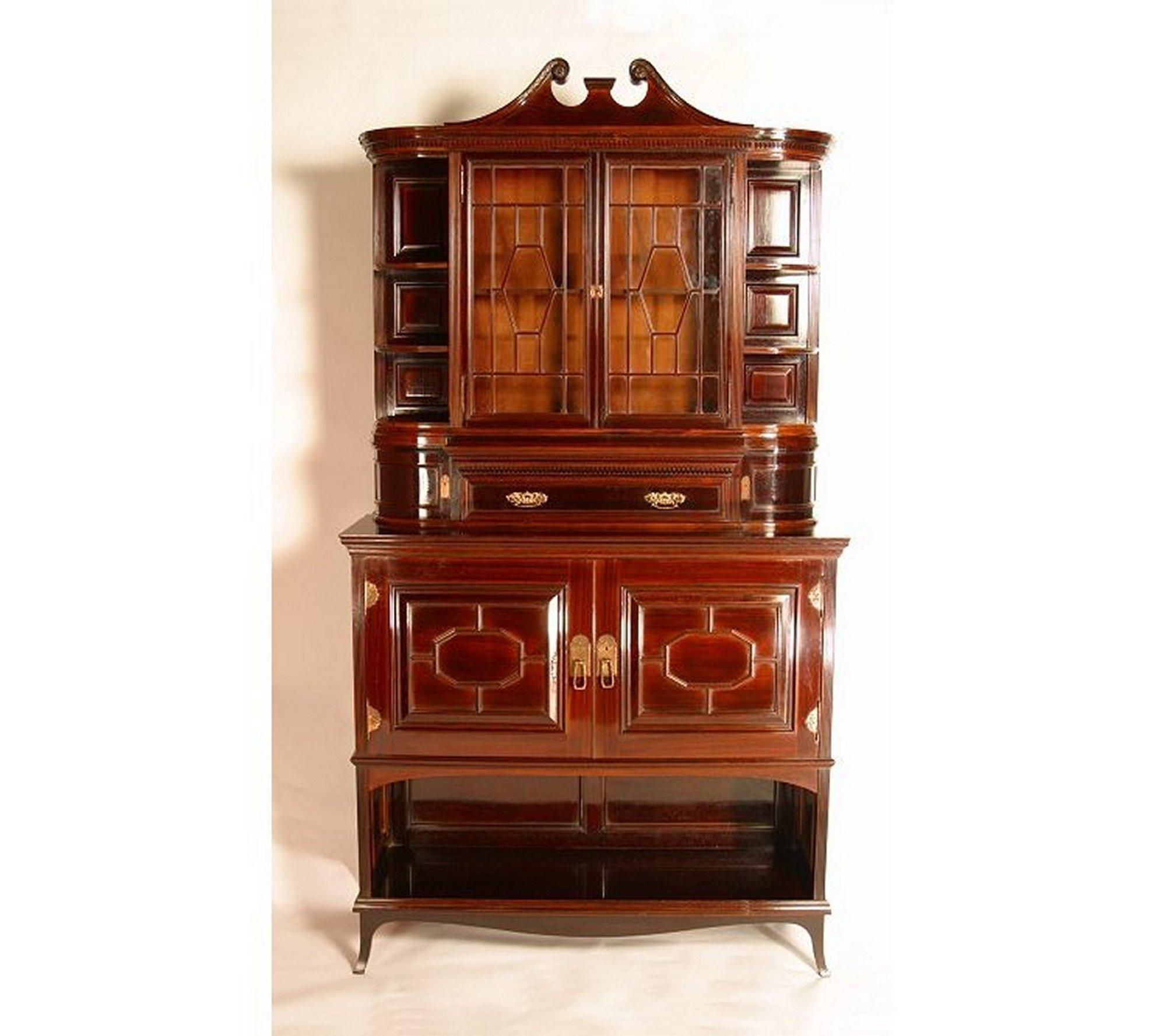 Edward William Godwin (1833-1886) for Collinson and Lock, The Eaton Hall cabinet, circa 1878, in rosewood, the scroll-carved broken arched Queen Anne pediment above a dentil and moulded frieze, with a pair of astragal glazed doors flanked by shelves