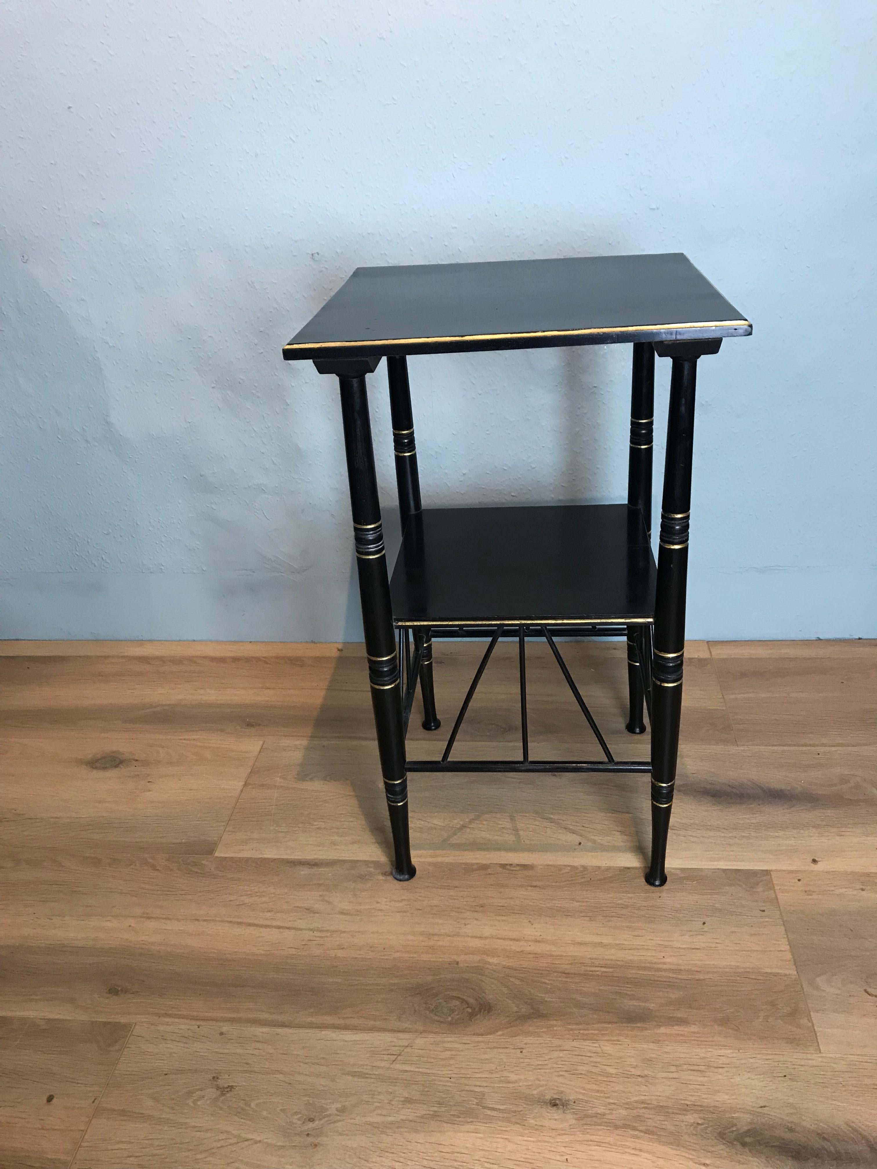 A delicate and slender ebony and parcel gilt E W Godwin style Aesthetic movement side table. This attractive table is in the Egyptian furniture design with elegant turned legs and fine angled brackets.