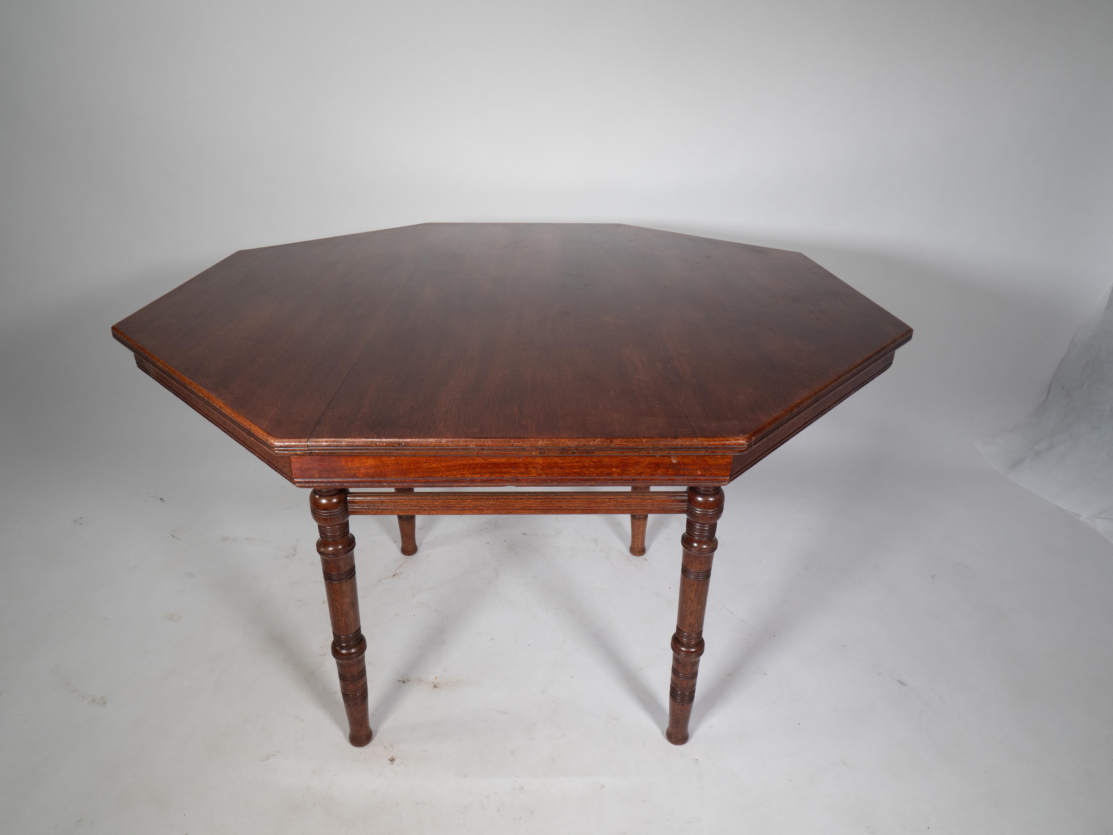 E W Godwin attributed. An Aesthetic Movement Walnut octagonal center table with tramline molded edges with fine turnings to the legs united by a high stretcher and standing on Thebes style legs.