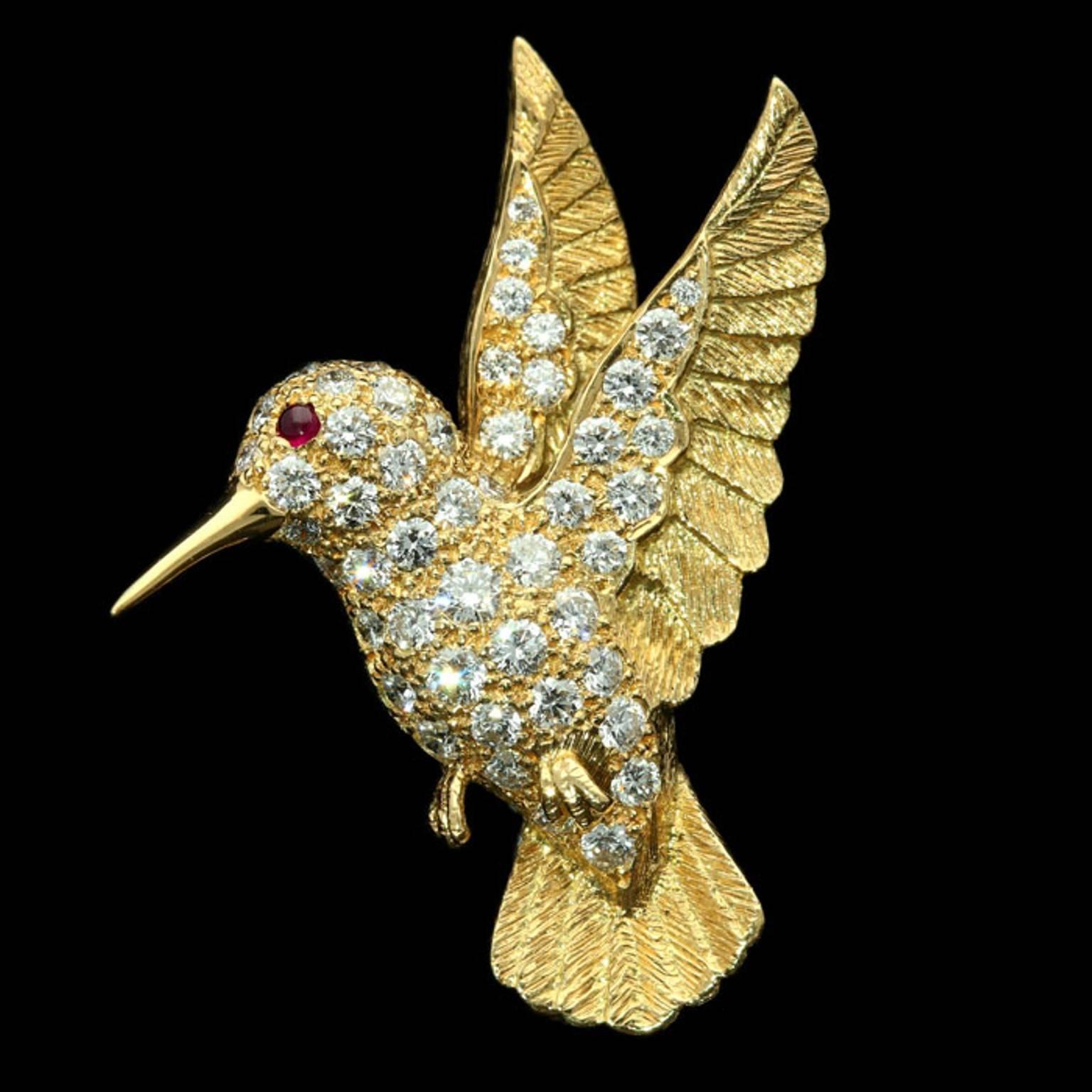 The charming brooch designed as a hummingbird in mid hover, the wings and tail with finely engraved feathers, the body pavé set with round brilliant cut diamonds and with a ruby cabochon eye.

Round brilliant cut diamonds weighing a total of
