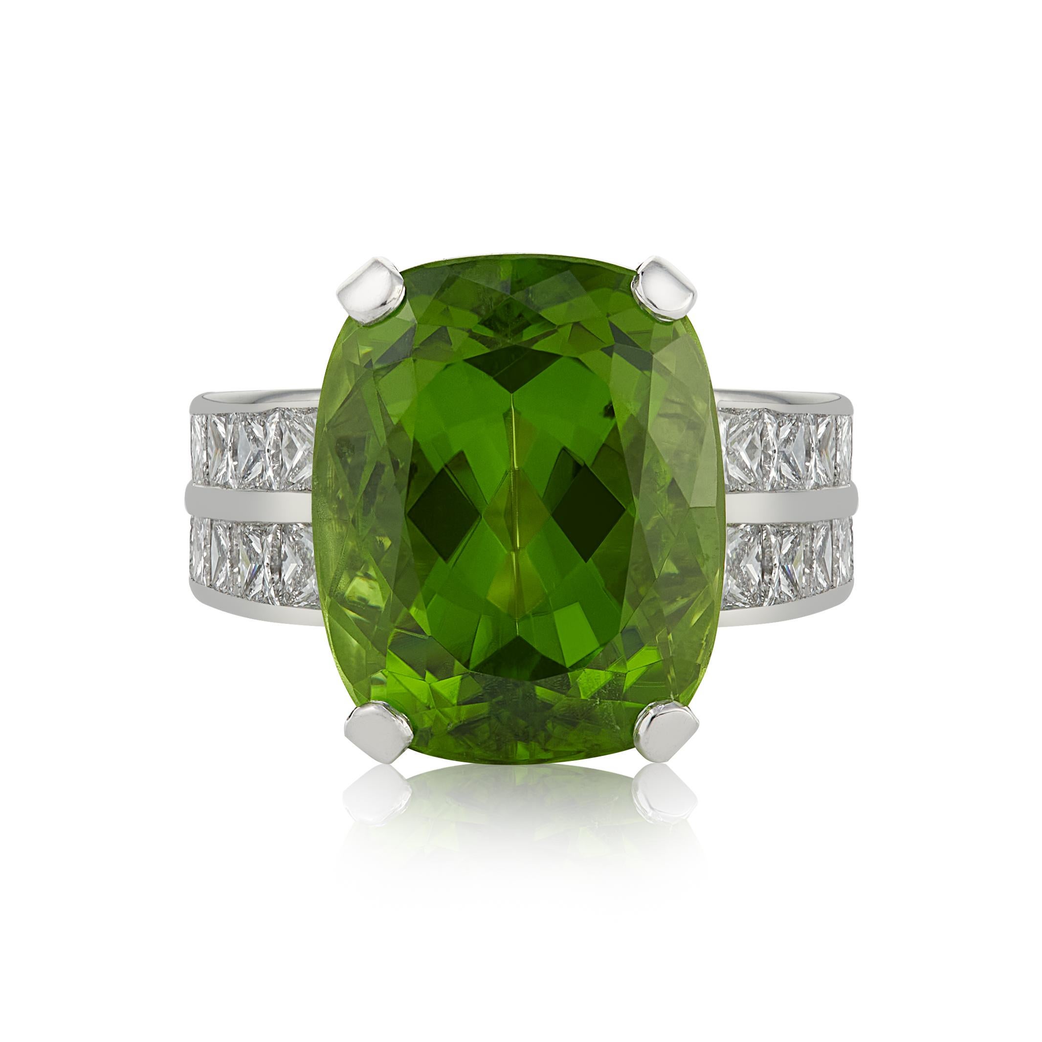 E Wolfe & Co Handmade 18ct White Gold Peridot and Diamond Cocktail Ring. The peridot centre stone weighs 12.33 carats, is of extremely good colour and has two rows of princess-cut diamonds set to either side of the white gold ring band. The