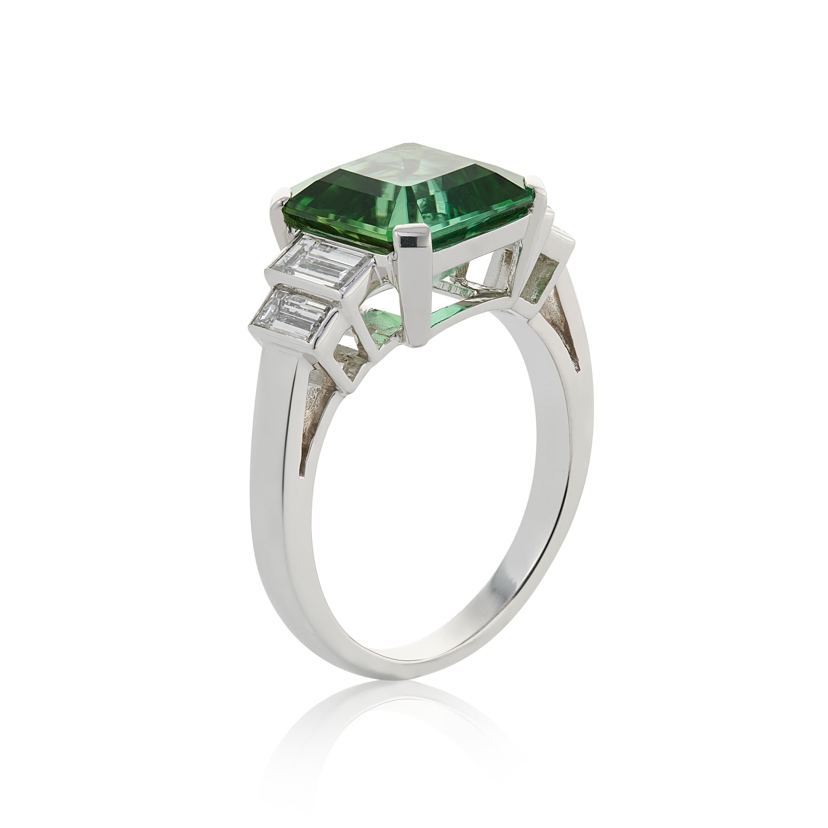 E Wolfe & Company Handmade 18ct White Gold Green Tourmaline and Diamond Baguette Ring. The green tourmaline centre stone weighs 3.59 carats and has two pairs of baguettes diamonds set to either side. The baguette diamonds have a total weight of .73