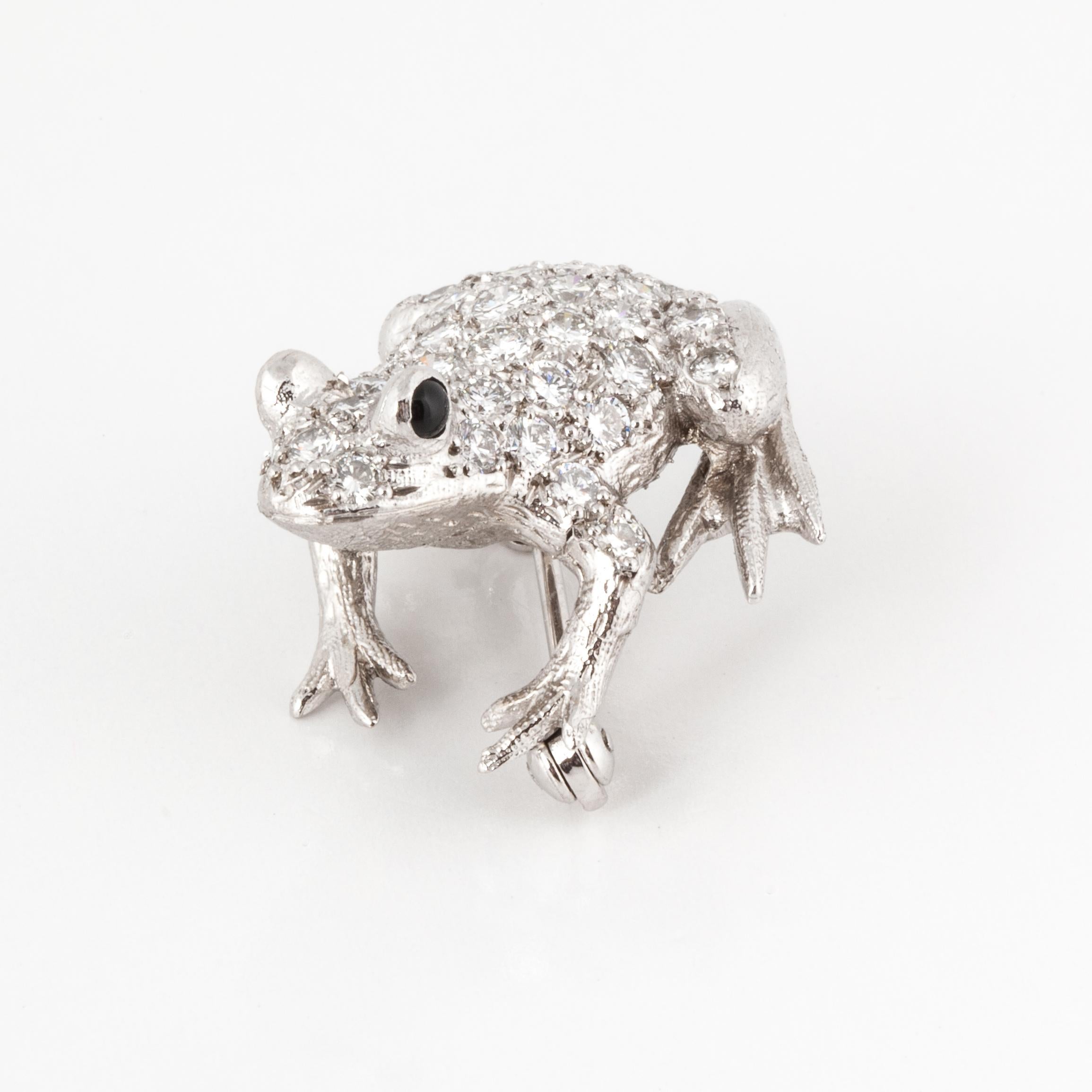 18K white gold frog pin by E. Wolfe & Co. that features 43 round diamonds totaling 1.95 carats; E-F color and VVS2-VS2 clarity.  The eyes are cabochon black onyx.  Measures 1 inch by 15/16 inches and is 1/2 inch deep.