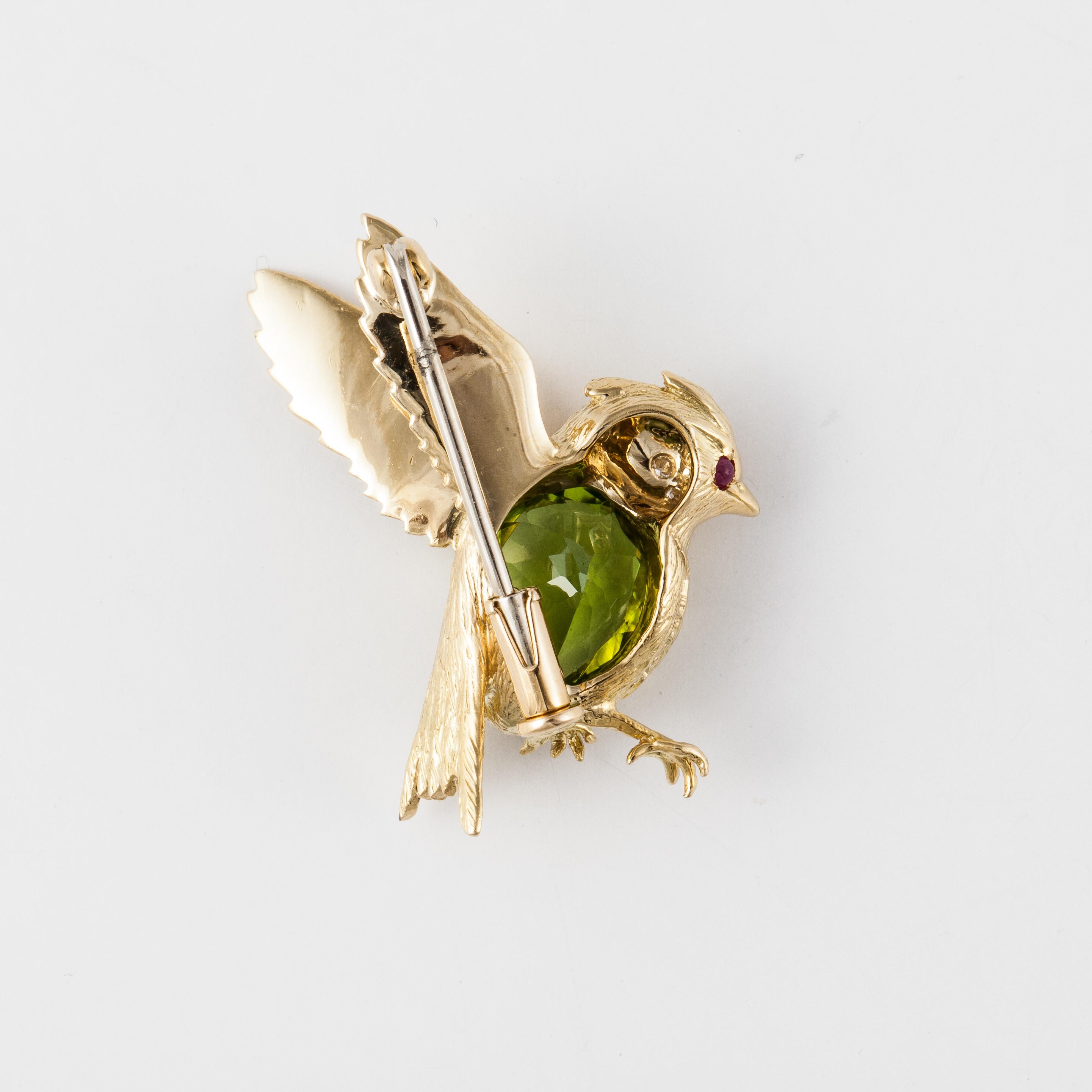 E. Wolfe pin composed of 18K yellow gold with peridot, diamonds and rubies.  The body is a pear-shaped peridot with five round diamonds that total 0.10 carats and two cabochon rubies in the head.  This pin measures 1 1/4 inches long and 7/8 inches