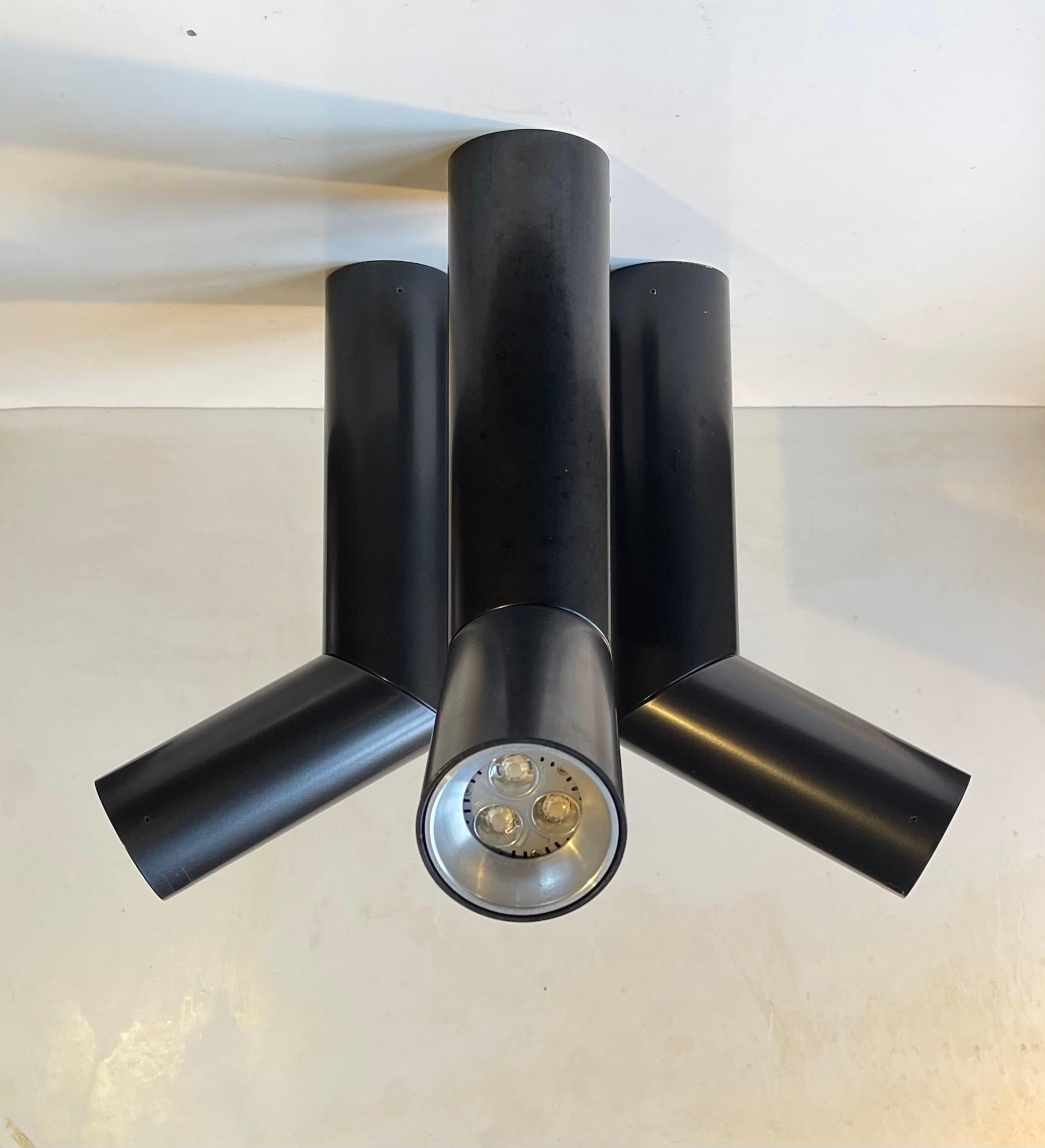 E06 is a family of adjustable luminaires with a cylindrical/tubular lamp body. Here a set of 3 in satin black. Designed by Habits Studio in 2008 and produced by the famous Luceplan brand. They feature a cylindrical body in extruded aluminum. It has