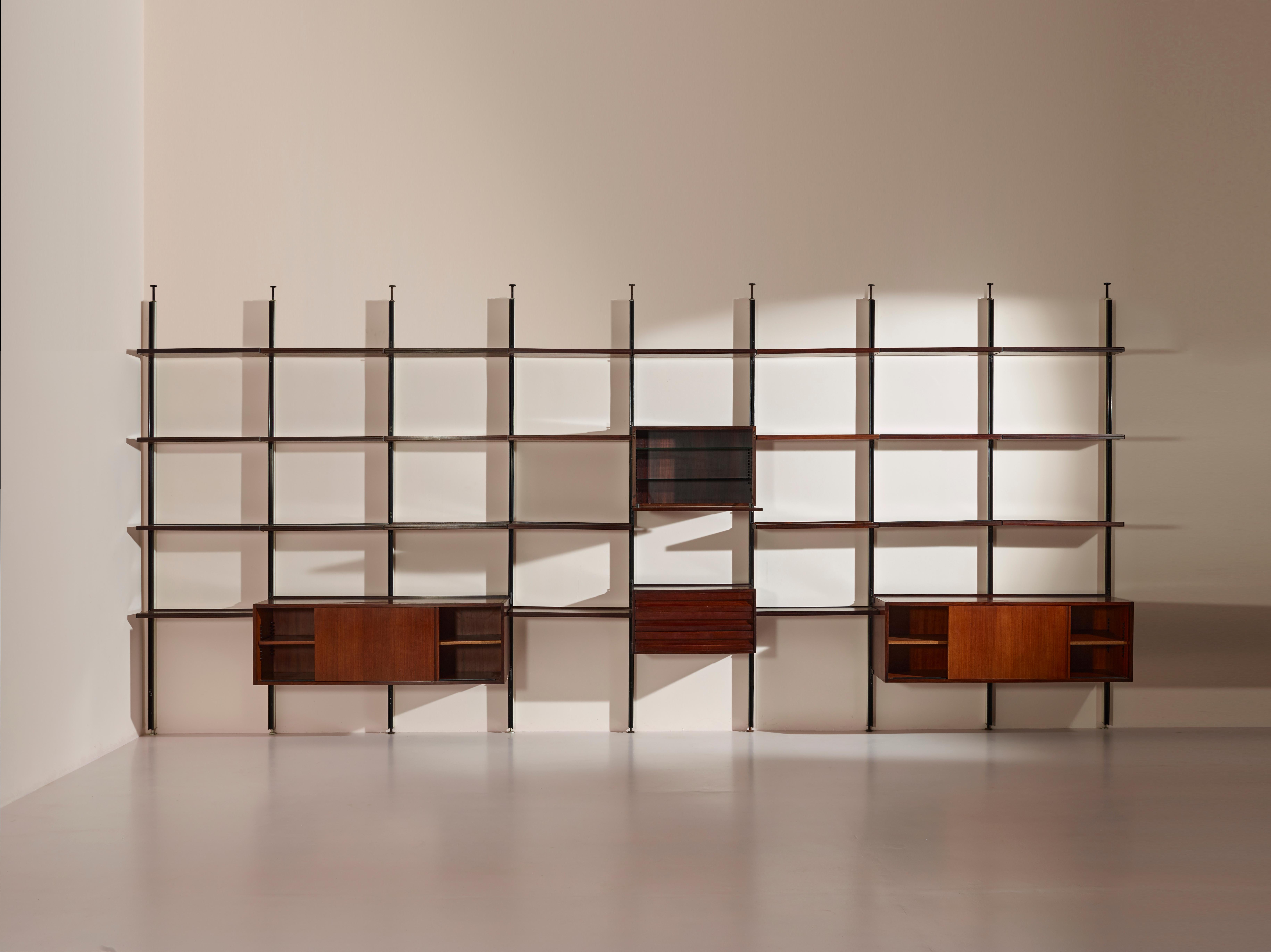 This large E22 bookcase or wall unit was designed by Osvaldo Borsani and manufactured by Tecno in the 1950s. It is constructed of metal, wood, and glass and measures 5.7 metres in width. The wall-mounted shelving unit consists of eight sections and