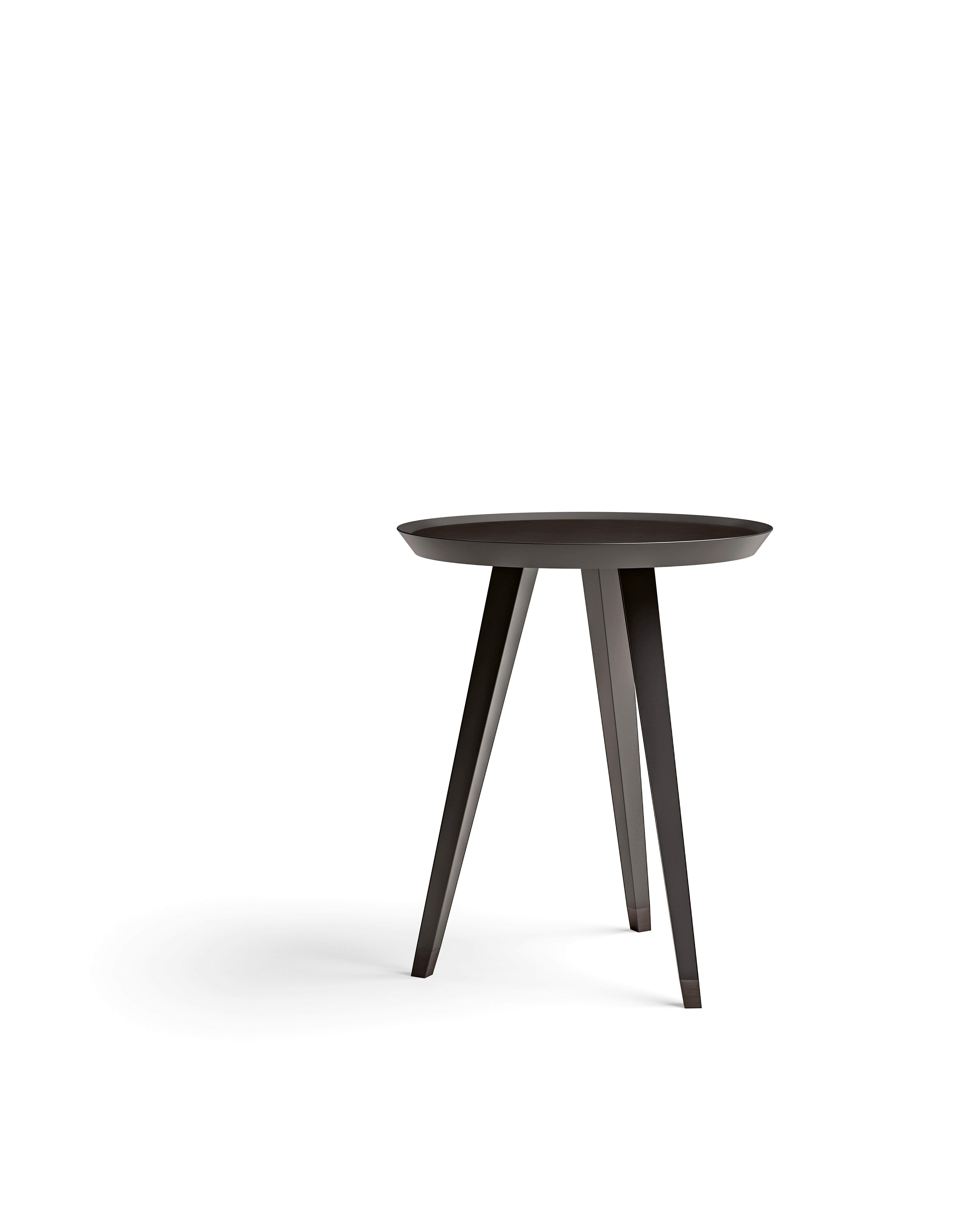 A high side table featuring a sleek metal top and a velvet lacquered base. The contrast between the shiny metal surface and the soft, luxurious velvet finish of the base creates a sophisticated, modern look. The table's height and elegant design
