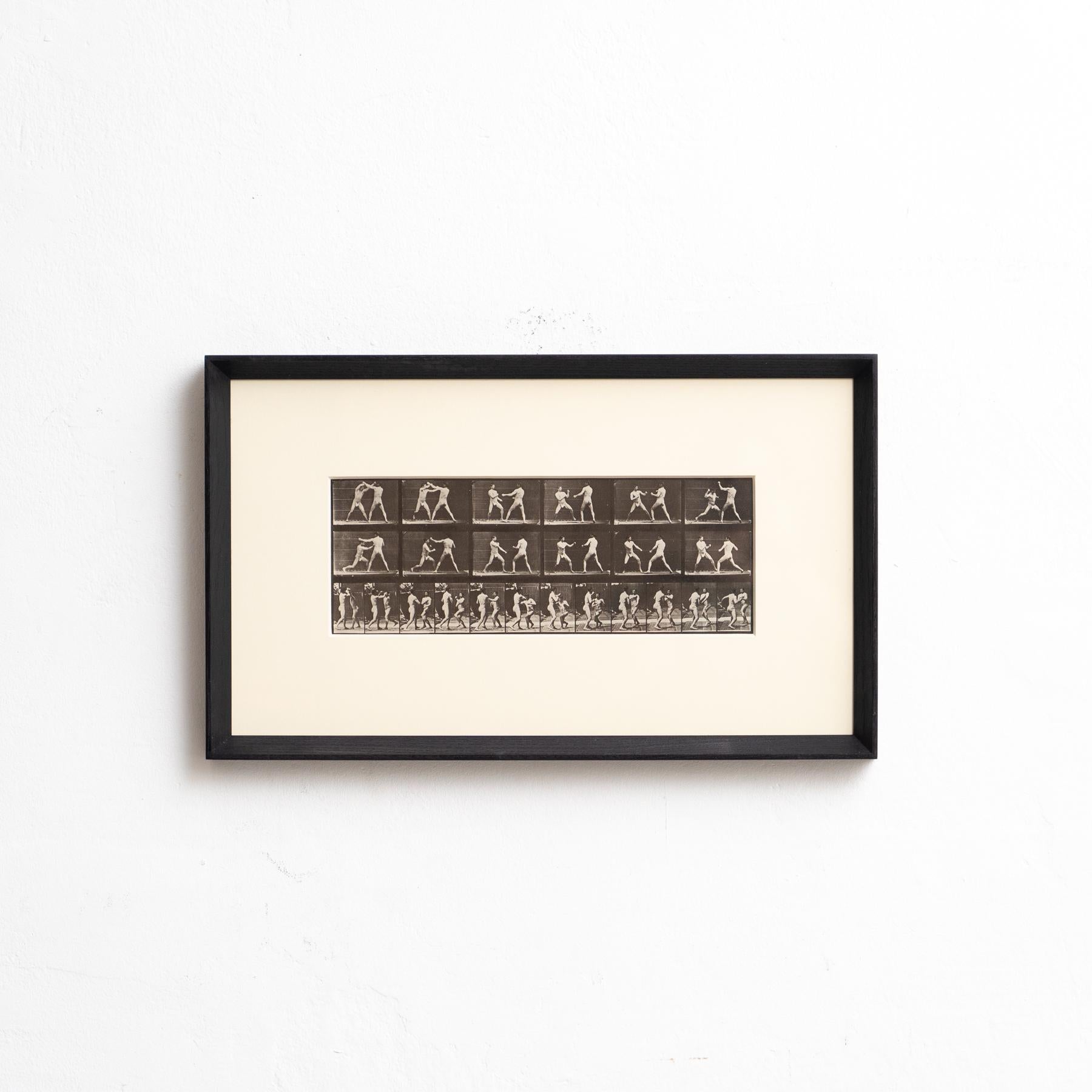 Explore the pioneering work of Eadweard Muybridge with this framed black and white photograph, capturing his iconic study of the movement of two men fighting. This photograph, printed in heliogravure, is part of a limited edition of 1000 copies,