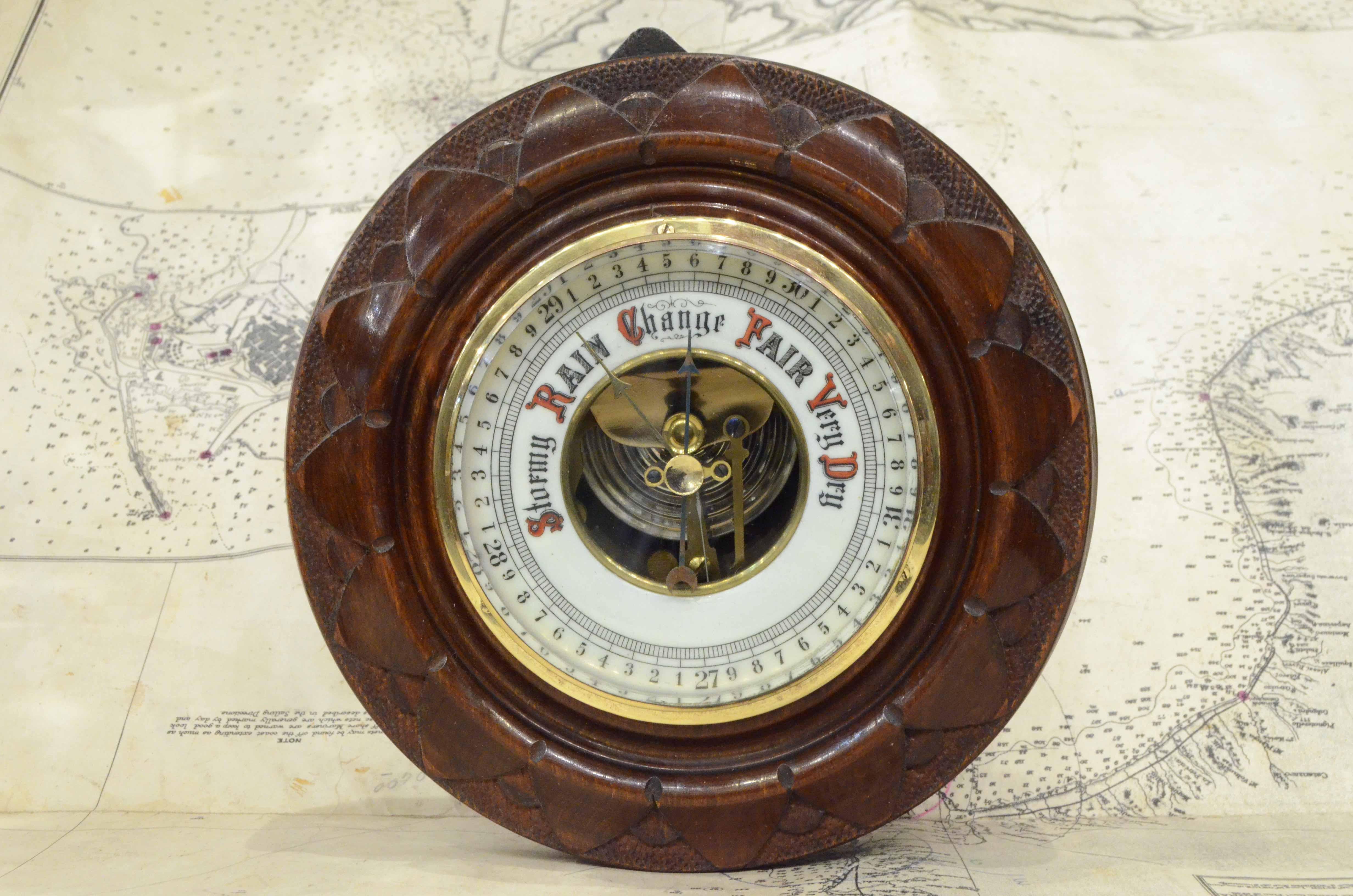 Antique English aneroid barometer, early 1900s, carved oak wood, glass and brass. 
Good condition and in order. 
Diameter cm 17 - inches 6.8, height cm 4.8 - inches 2.9. 

It’s an antique measuring instrument having an element sensitive to