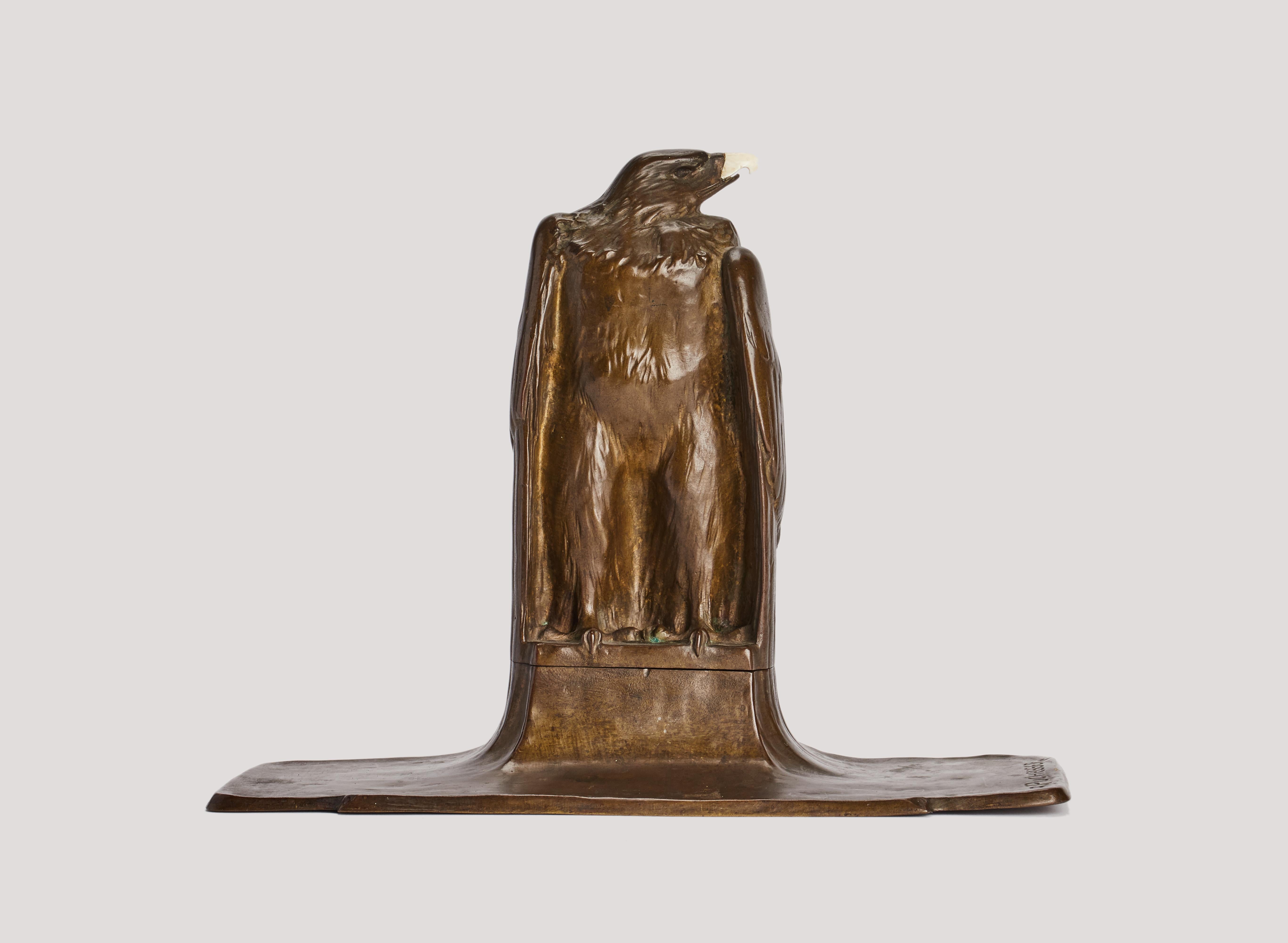Bronze inkwell depicting a standing eagle with folded wings. The sculpture rises on a rectangular base and, as it rotates, reveals the white ceramic ink container. Stag horn beak. Signed A.Puchegger (1878 – 1917). Austria, ca. 1890.