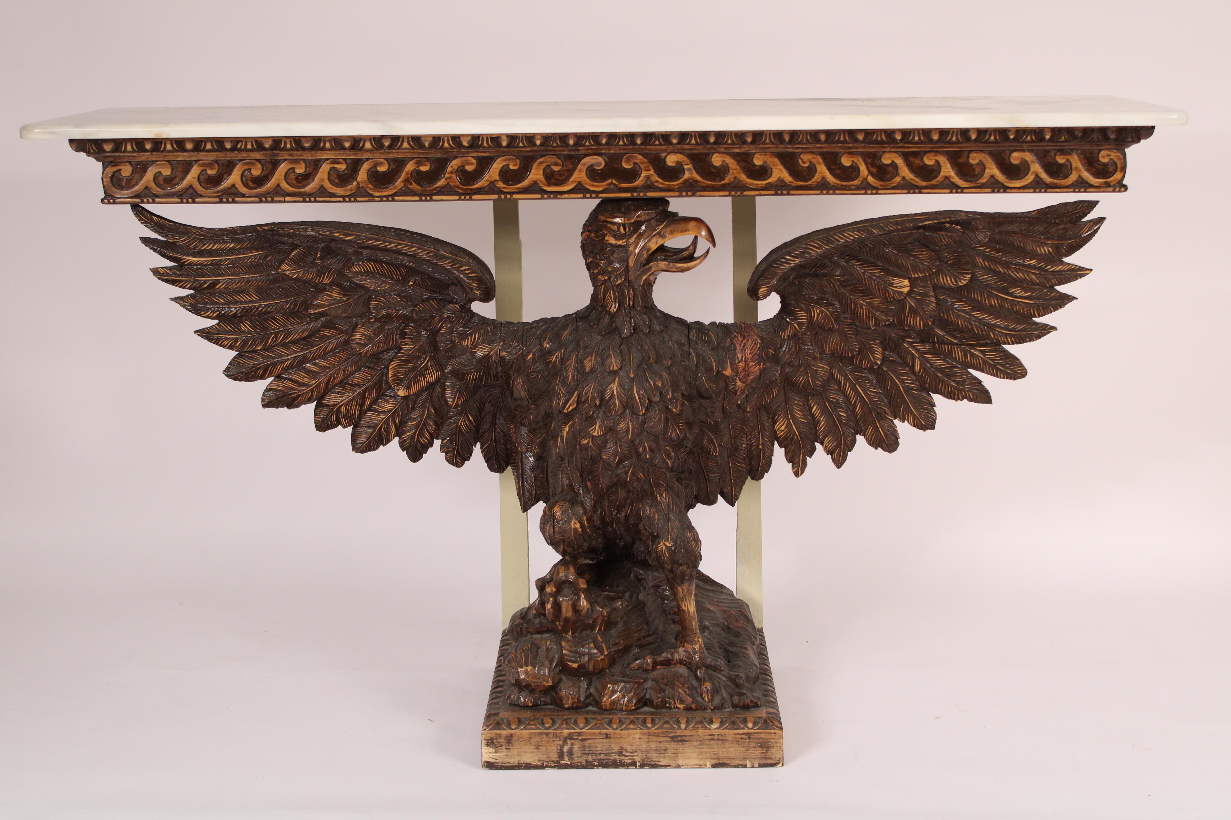 Neo classical style wood carved eagle form console table with a marble top, circa 1950's. With a rectangular white marble top with rounded front corners, a wood carved eagle with wings expanded standing on a rock work base resting on a plinth base