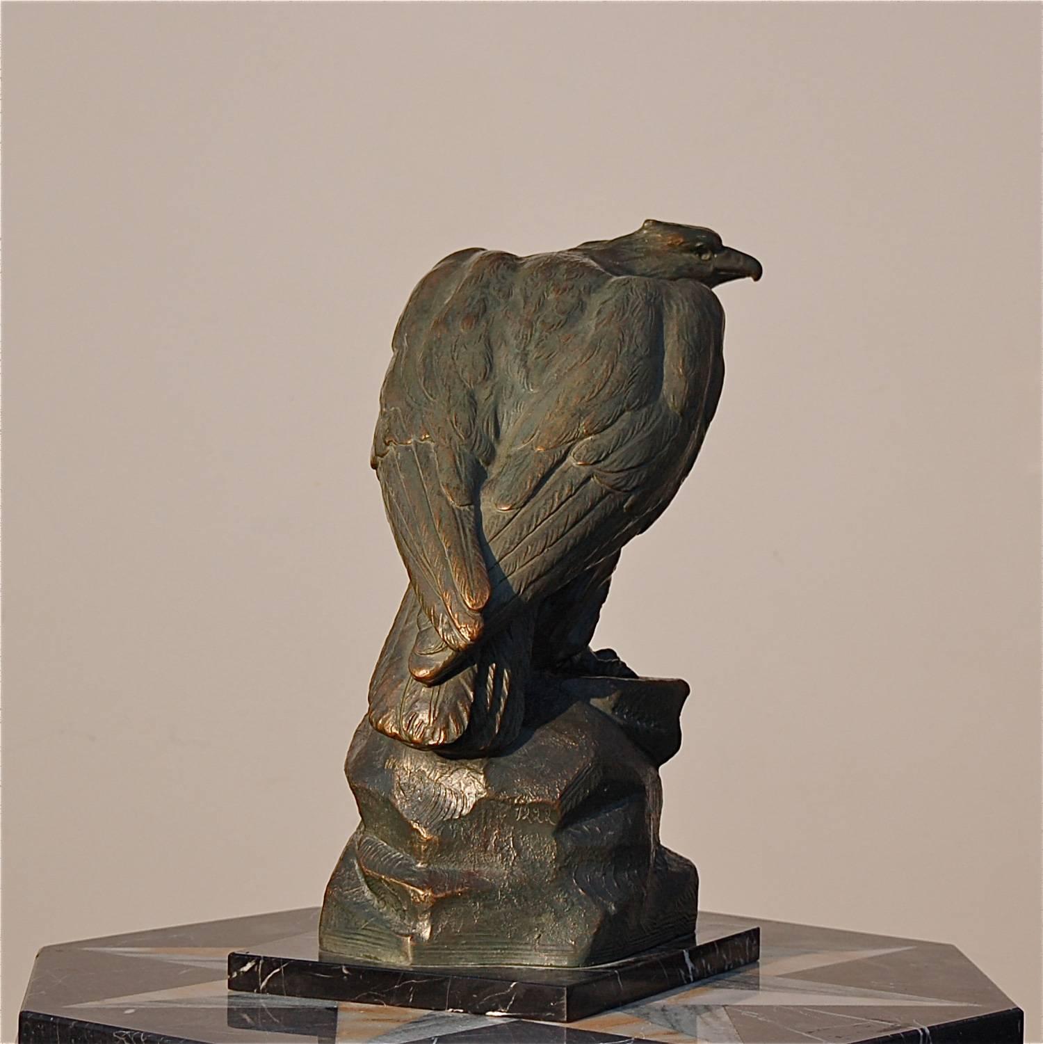 Early 20th century statue of a characterful eagle resting on a rock. The artist crafted the bird of prey from terracotta or plaster which was subsequently professionally patinated to match or mimic bronze. Numbered, but unclearly signed. The statue
