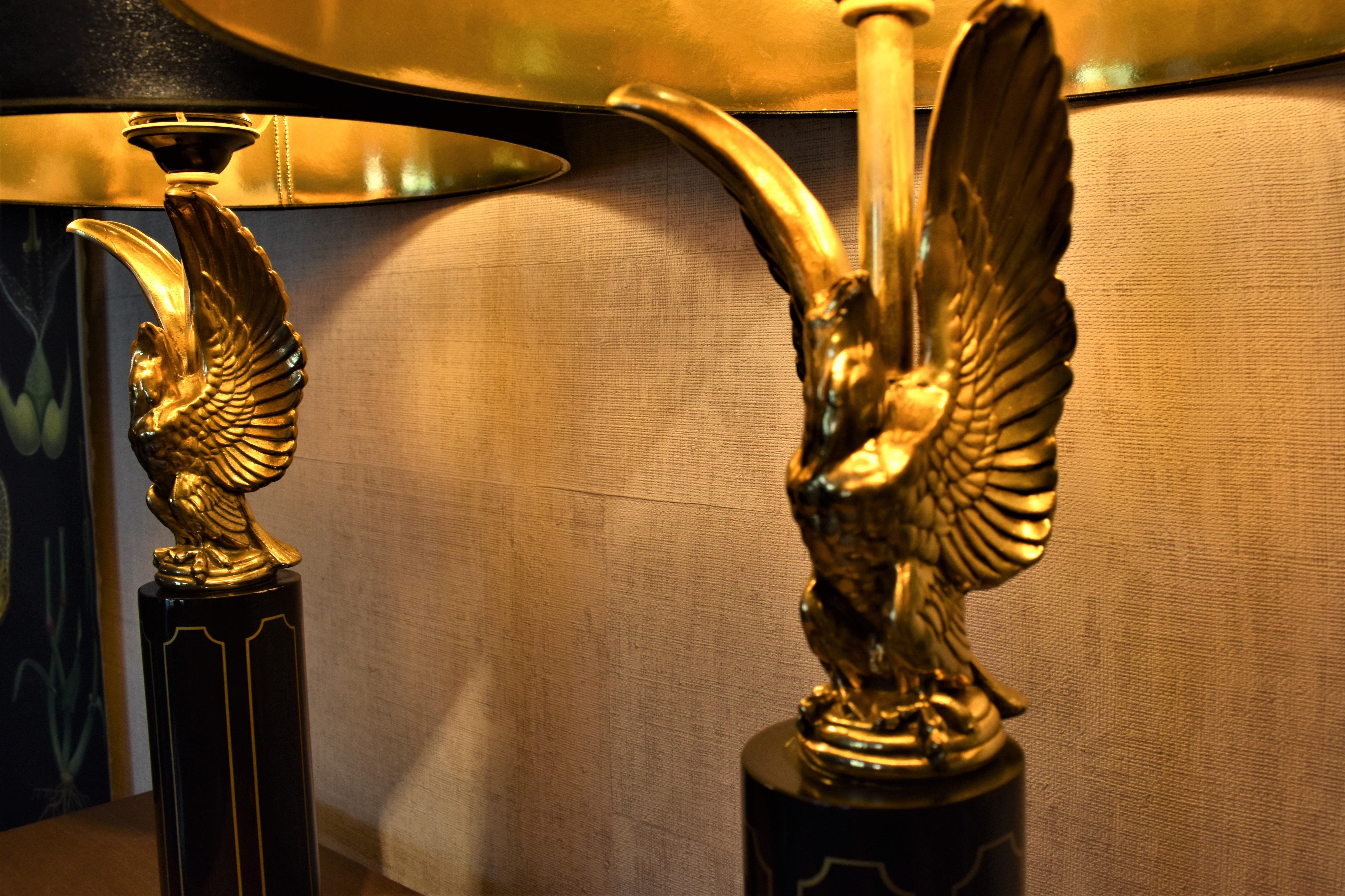 A pair of original Hollywood regency table lamps attributed to Maison Charles dating from the 1970’s. The lamps consist of gold eagles mounted on a lacquered base and have a beautiful patina. 

The original shades with gold insides will be given