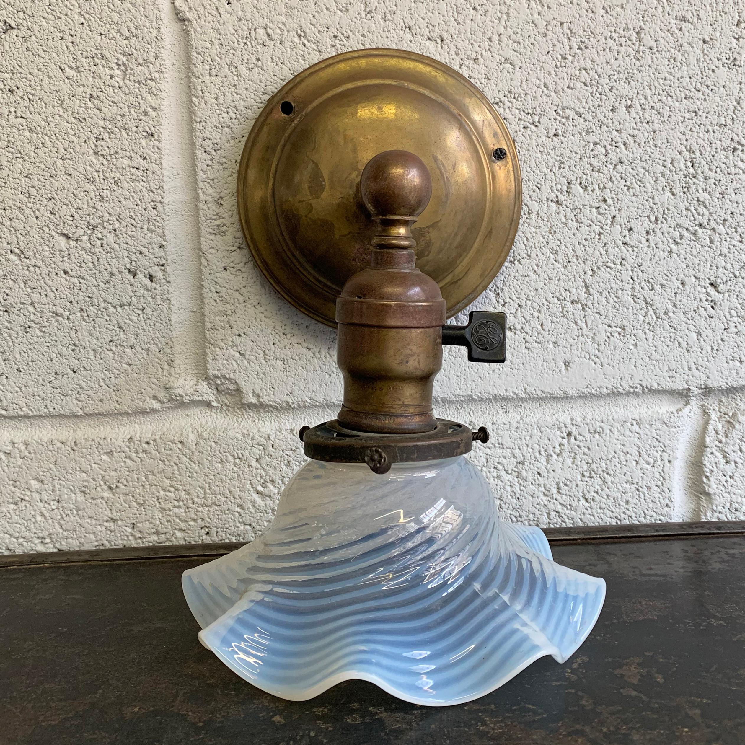 Early 20th century, antique, industrial, brass wall sconce light features a pie crust ruffle, opaline shade and paddle switch. The shade diameter is 6 inches and the backplate is 5 inches diameter.