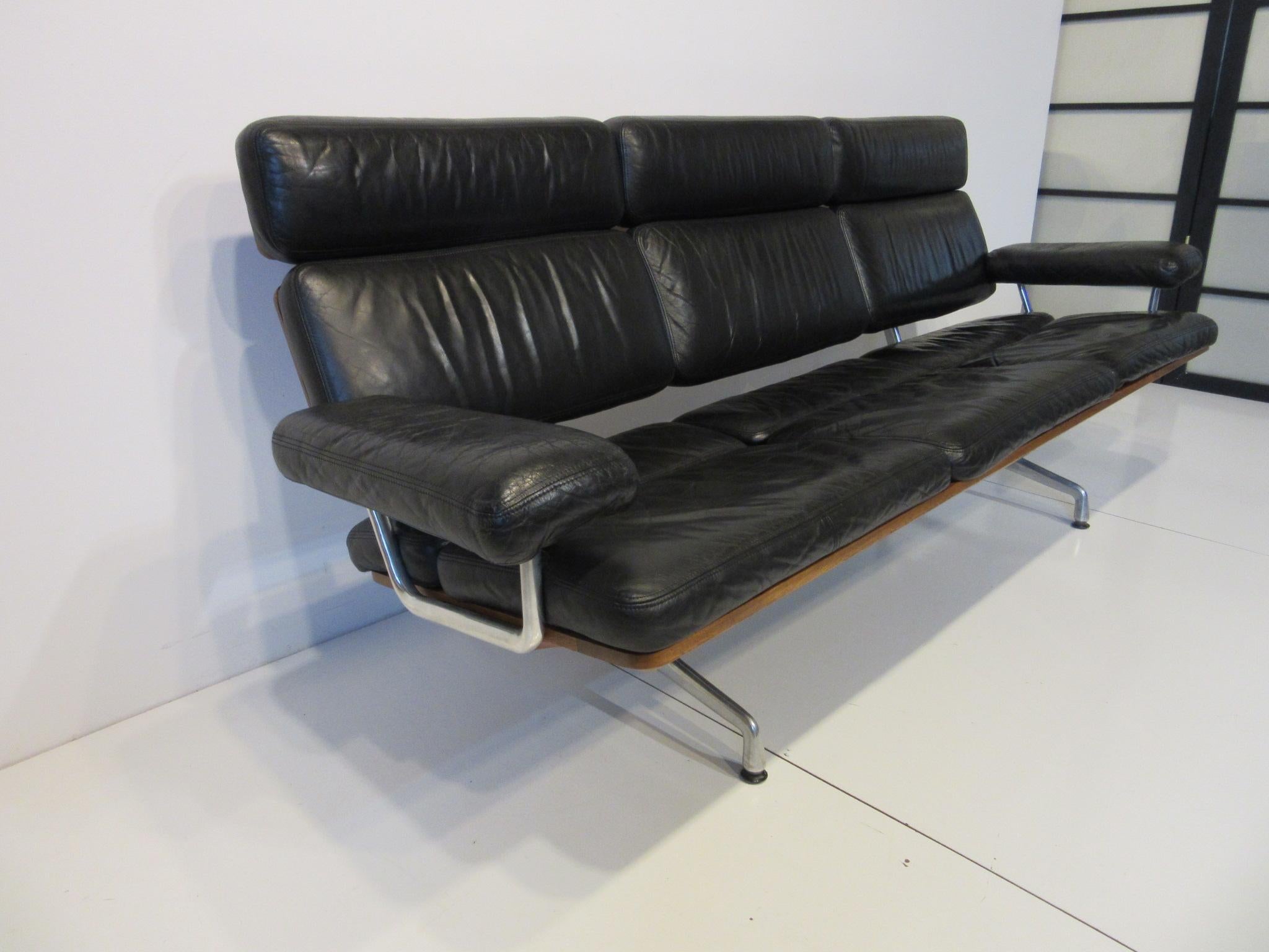 A rare and hard to find top of the line well crafted black leather soft pad sofa, with beautiful medium walnut back and cast aluminum legs. Model number 3473 one of the last designs put into production that was designed by the Charles Eames office.
