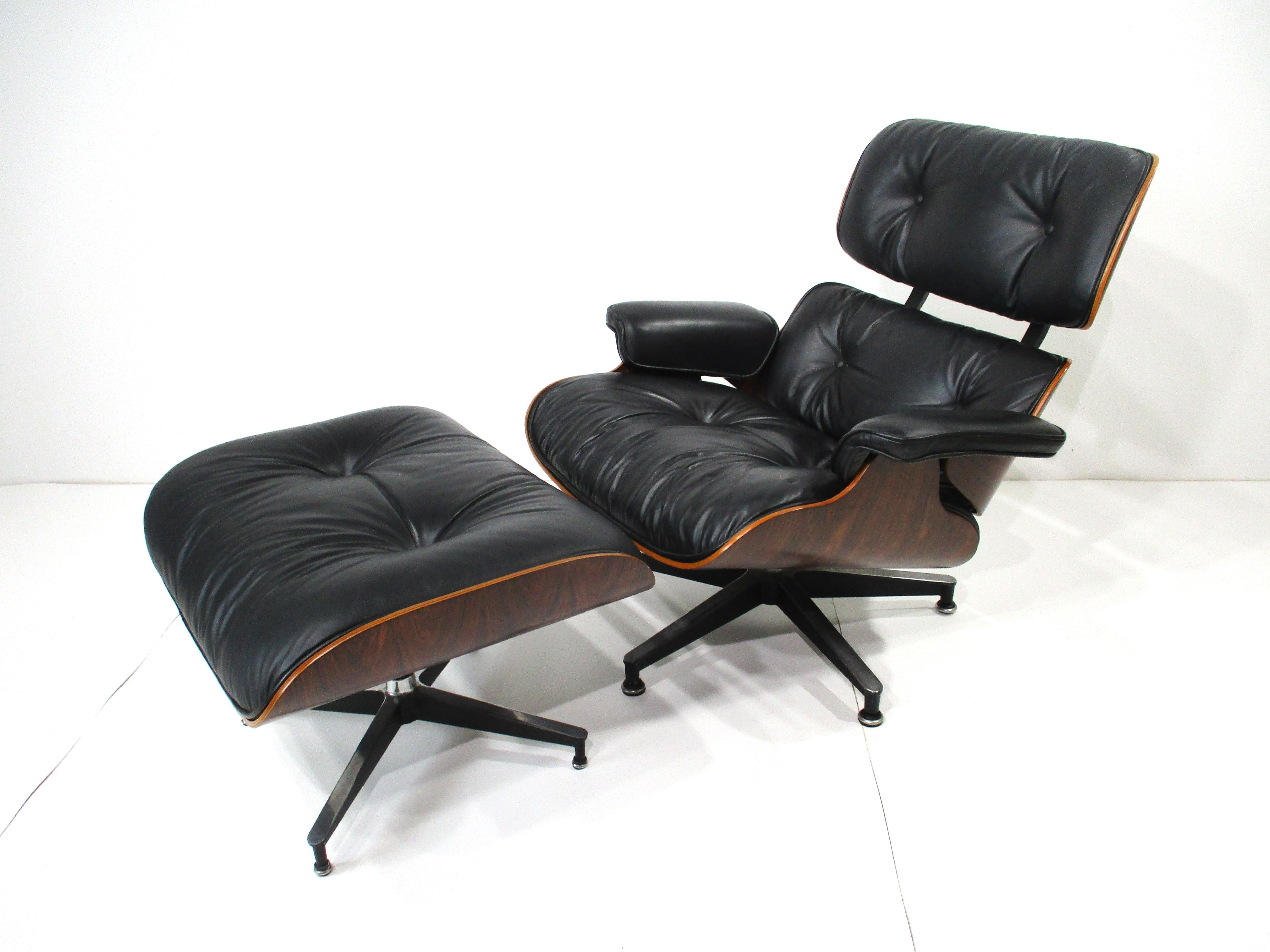 One of the most iconic designs of the Mid Century period the Eames 670 lounge chair with 671 ottoman . In the very desirable soft black leather and enhanced even further with a rich Brazilian rosewood frame sitting on cast aluminum star bases