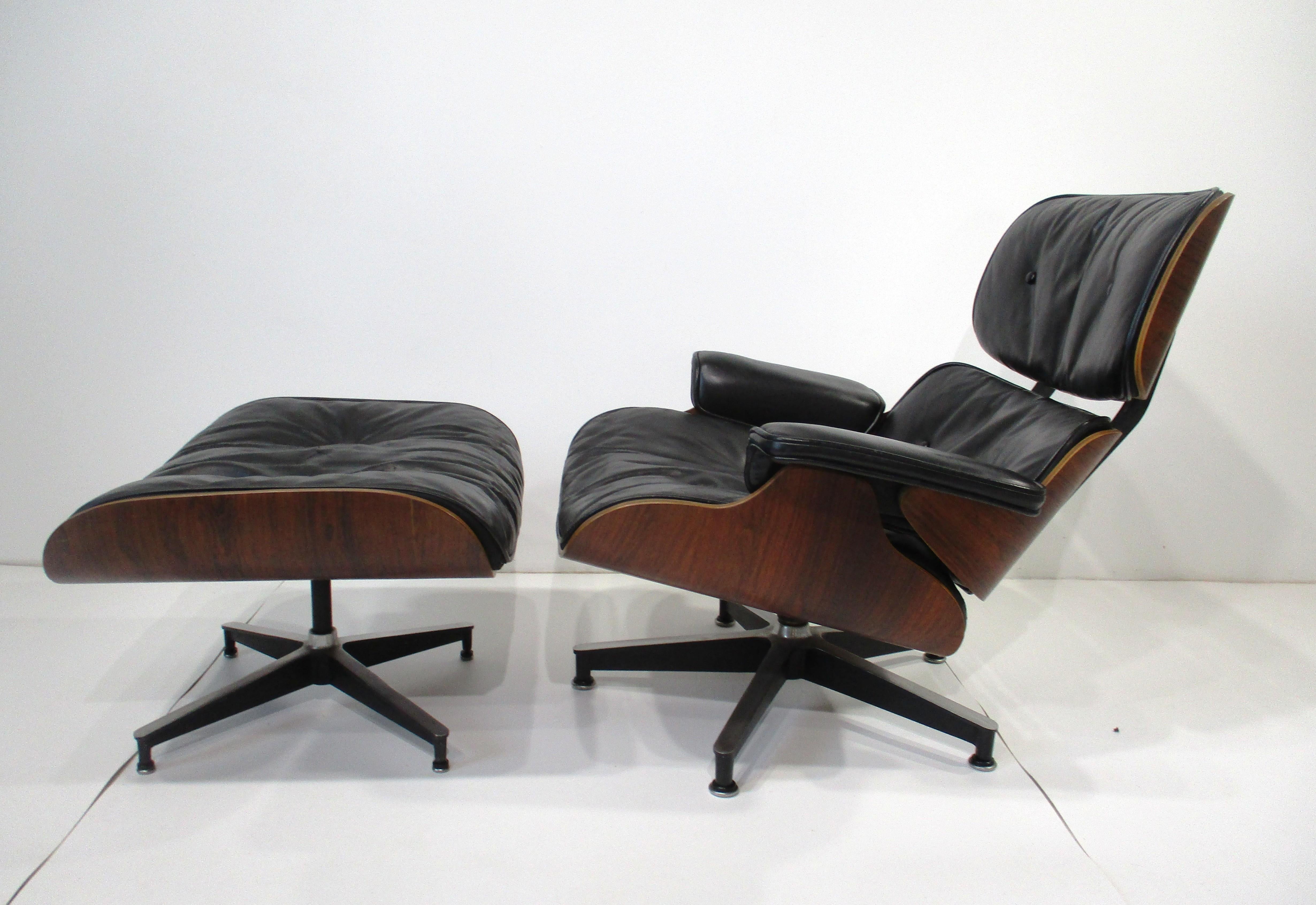 One of the most iconic designs of the Mid Century period the Eames 670 lounge chair with 671 ottoman . In the very desirable black leather and enhanced even further with a rich Brazilian rosewood frame sitting on cast aluminum star bases