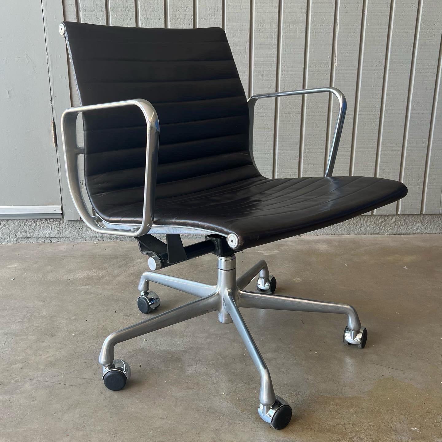 Eames Aluminum Group management chair for Herman Miller. I believe the color is Espresso or Slate (very dark grey/brown, almost black) Vicenza leather with a polished aluminum base on casters. Labeled as these were labeled in the early 2000s with a