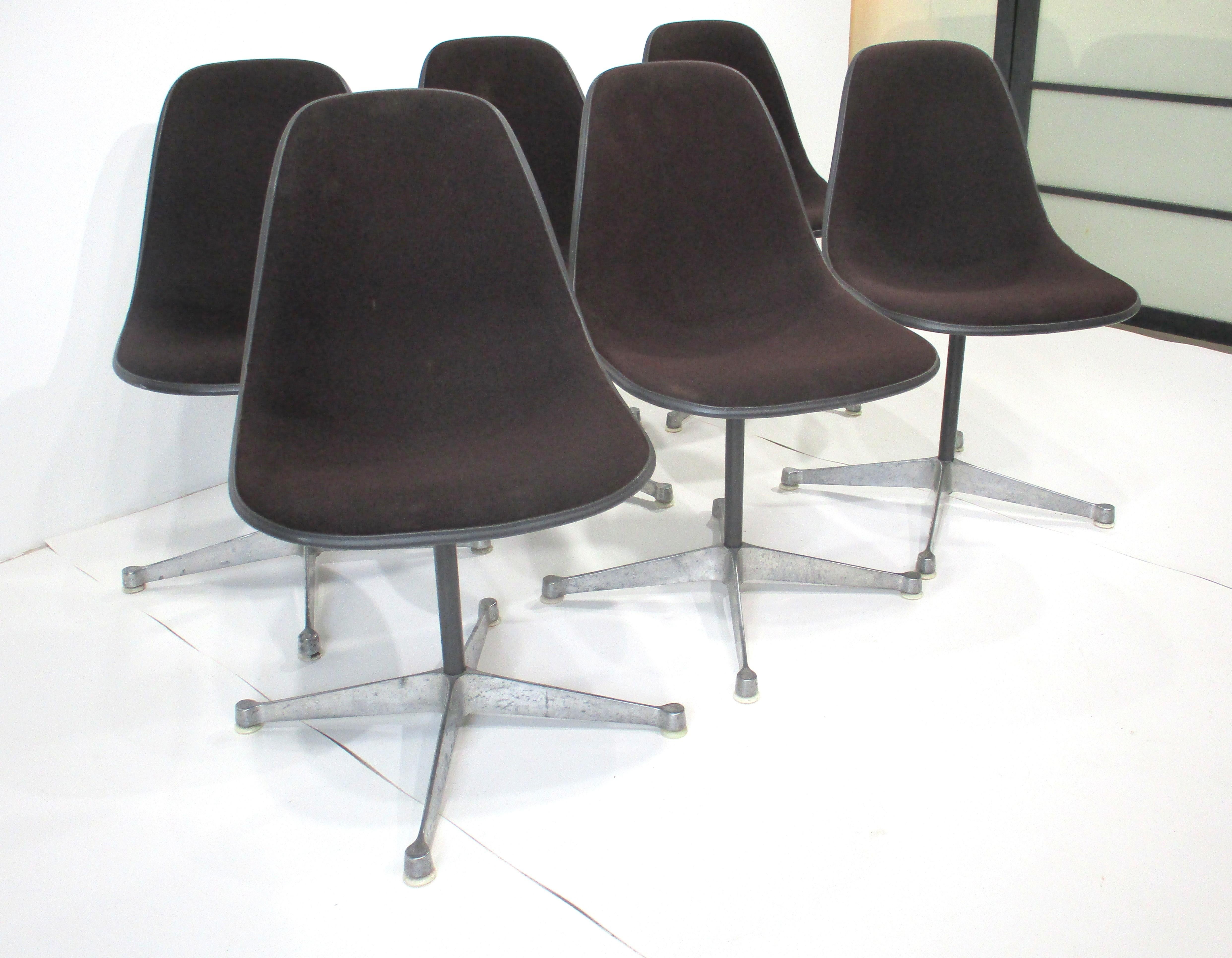 A set of six swiveling brown upholstered scoop dining chairs from the Aluminum Group collection .  Sitting on four star cast aluminum bases with foot pads to protect your floors , manufactured by the Herman Miller furniture company and designed by
