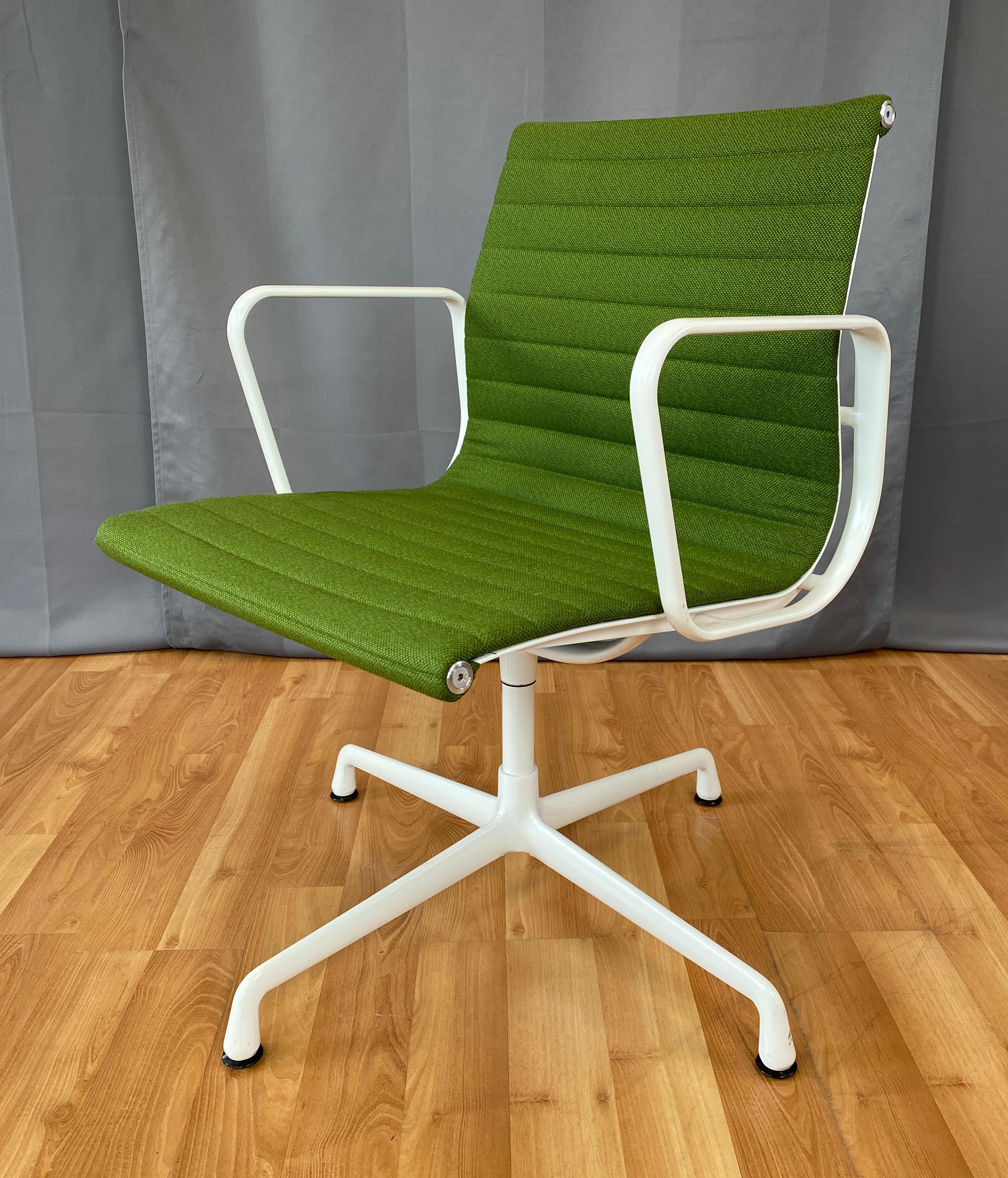 Offered here is a Eames aluminum group side chair, with arms. 
Has a white frame. And light Olive green upholstery, that feels to be wool. 
First designed in 1958, this one is circa 2000's.
  
