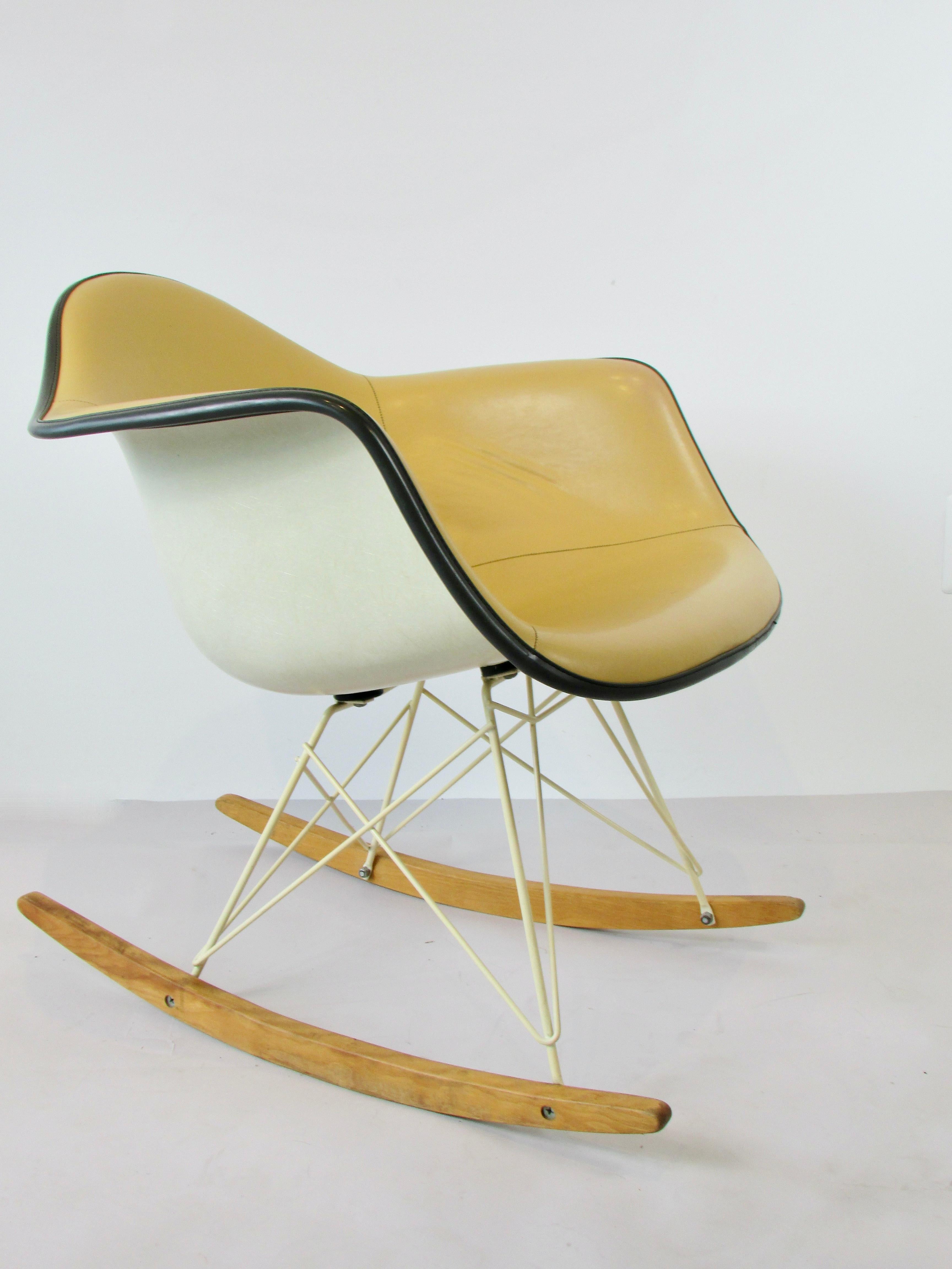 Charles and Ray Eames designed RAR rocking chair. Somewhat scarce or rarely seen coated white base. Fiberglass shell upholstered in butterscotch vinyl. Upholstery is puckering and pulling away from the shell. No rips or tears. The chair still sits