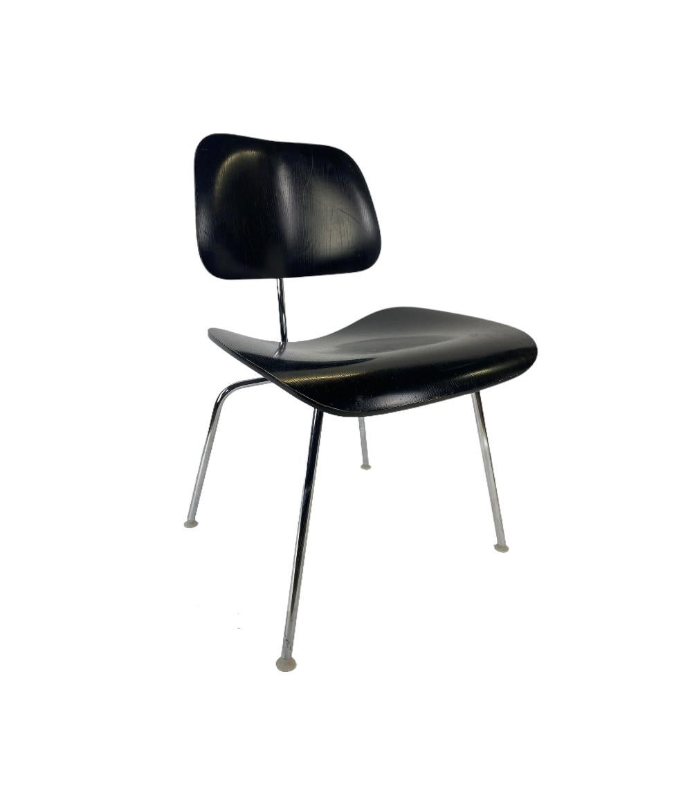 Klassischer Eames DCM Esszimmerstuhl in Schwarz. Sitz und Rückenlehne aus farbigem Eschenholz mit verchromtem Gestell. Selbstnivellierende, intakte Nylongleiter, die die Verwendung auf verschiedenen Oberflächen ermöglichen. Signiert und garantiert