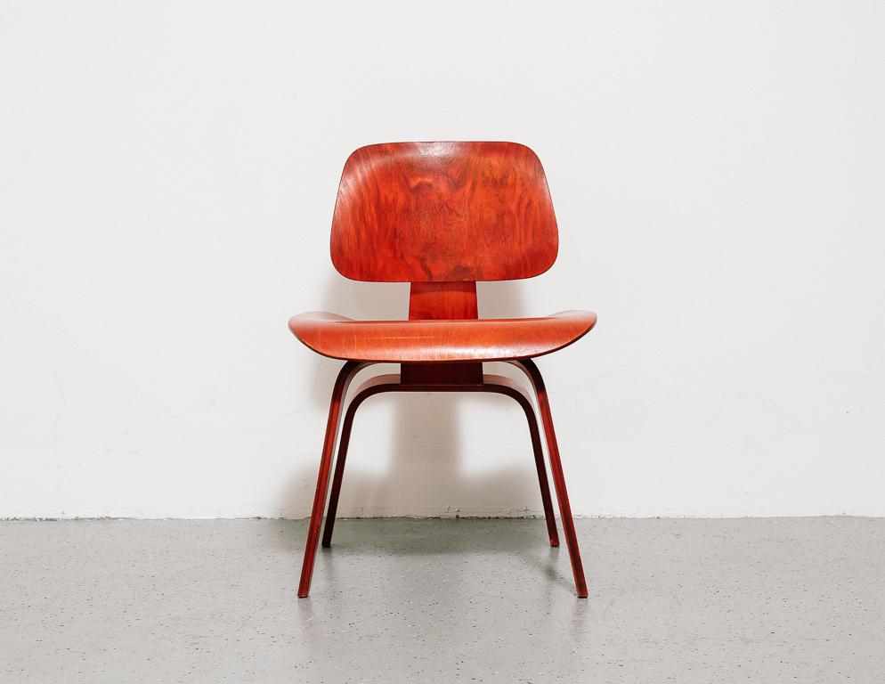 1950s Eames DCW (Dining chair wood) for Herman Miller bearing its original red aniline dye finish. Constructed of molded plywood.
