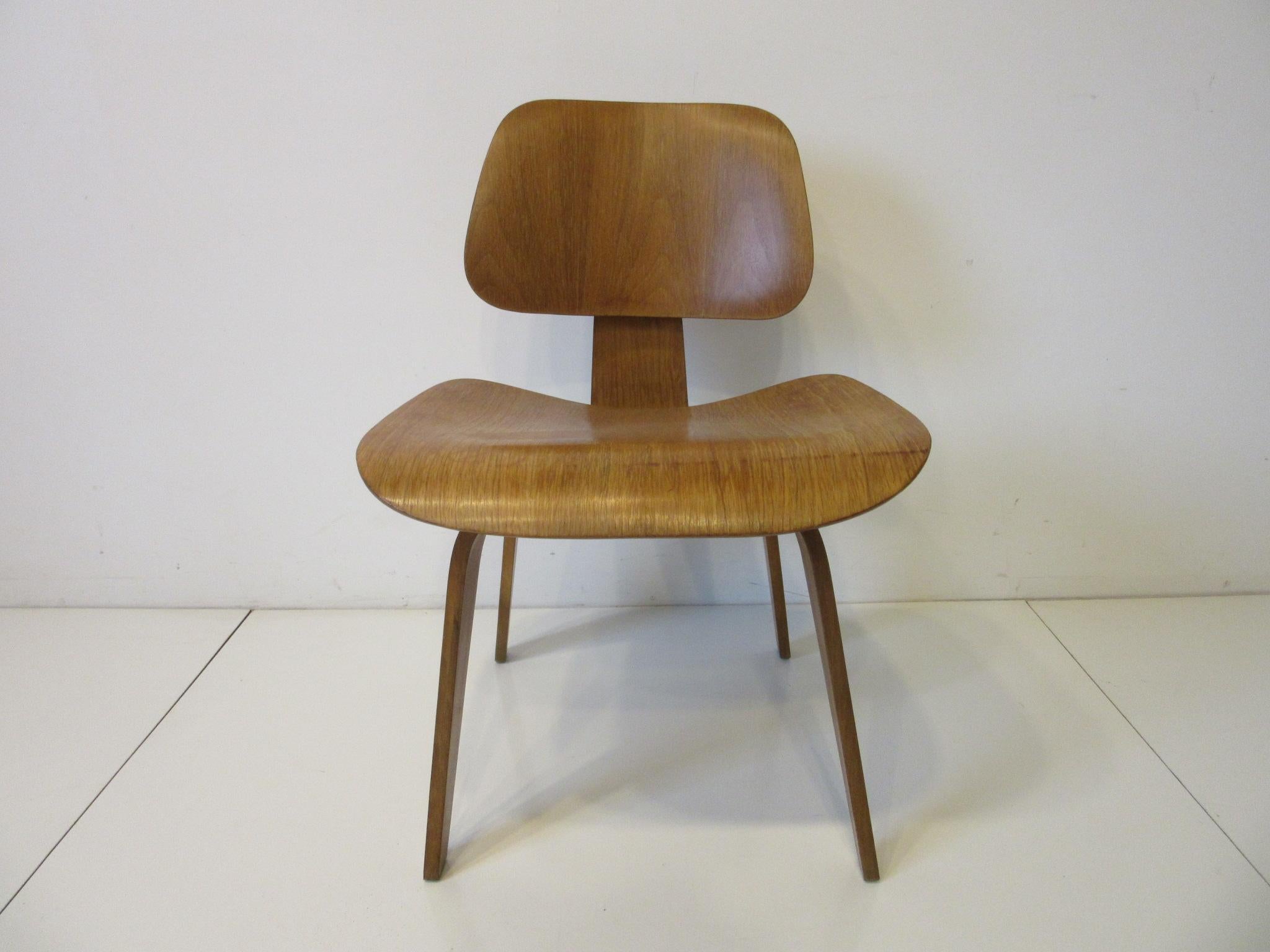 A DCW dining or desk chair wood, this earlier production molded plywood chair designed by Charles and Ray Eames is the classic standard of midcentury furniture. A sculptural timeless design far ahead of the rest and still fresh today manufactured by