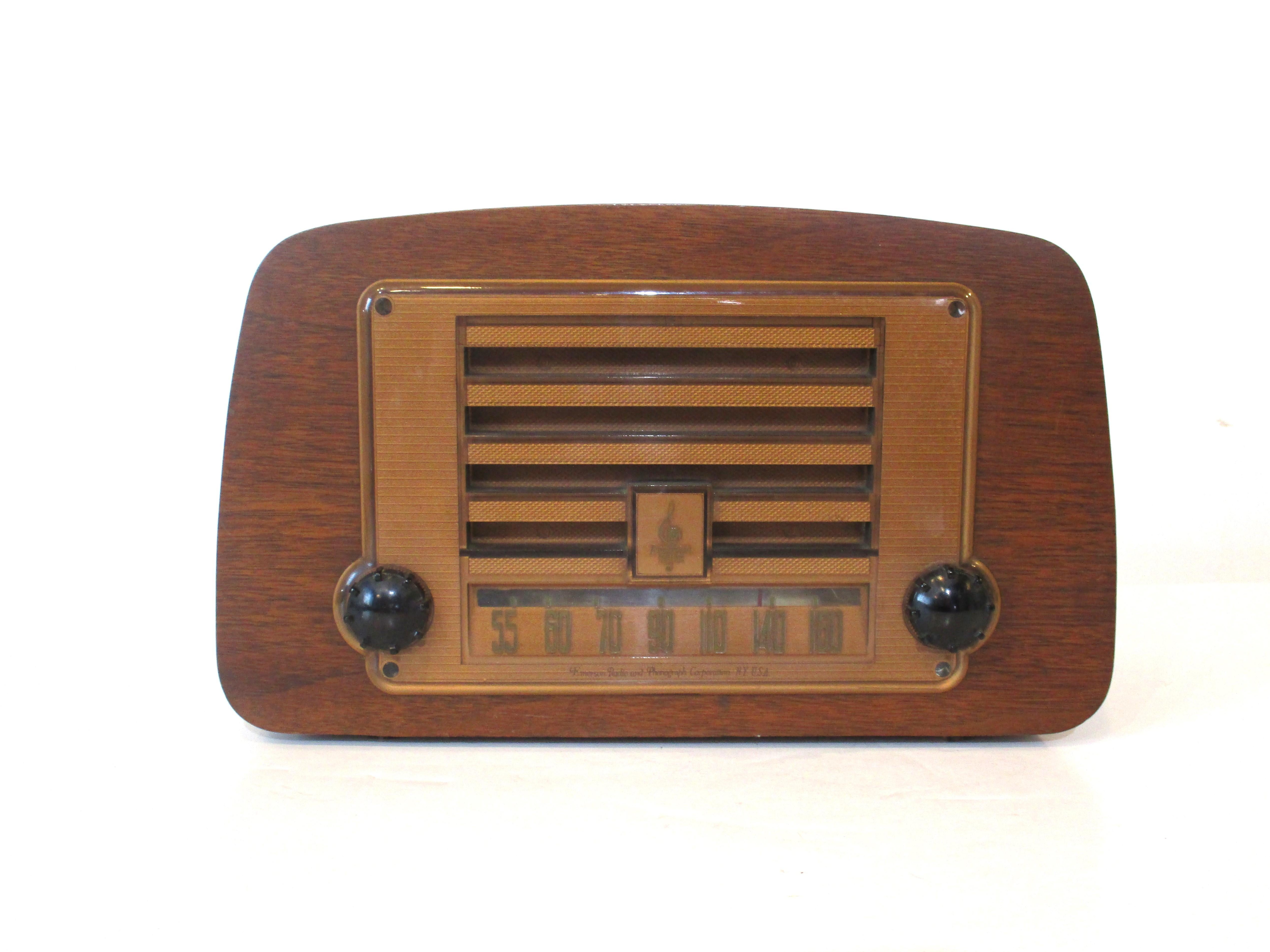 A walnut bent wood ply formed radio with colored plastic grill and knobs designed by the iconic team of Ray and Charles Eames. The couple designed some industrial items before their well known collaboration with the Herman Miller furniture company
