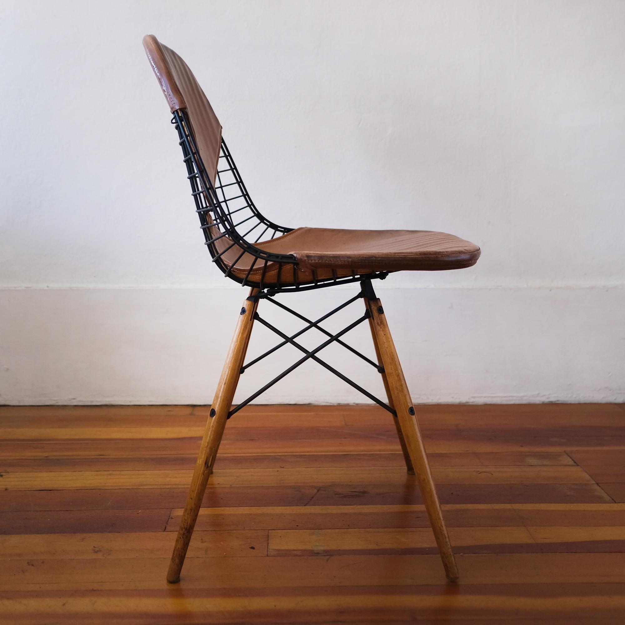 Charles and Ray Eames DKW-2 swivel dowel wire chair with postman bag leather bikini cover. All original with beautiful age appropriate patina.

Labeled: Herman Miller Furniture Company Venice, California.