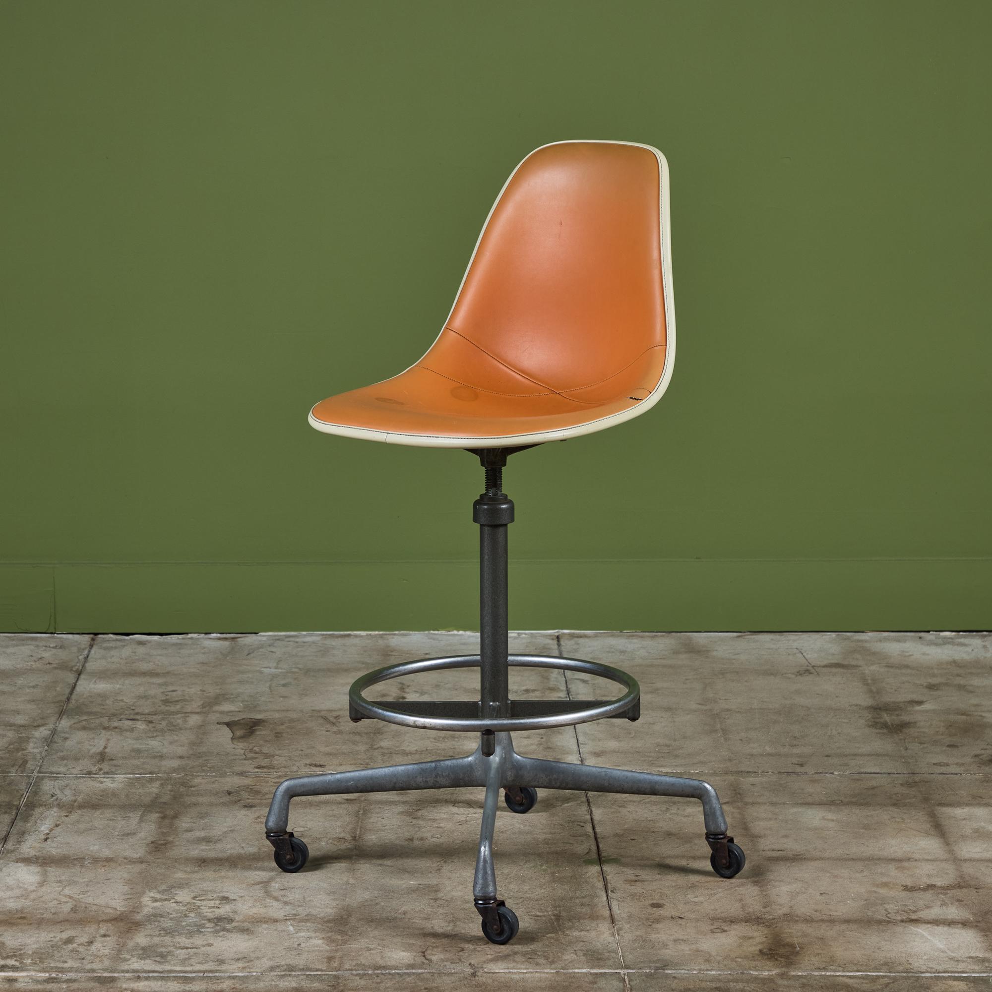 Swivel stool by Charles and Ray Eames for Herman Miller, c.1970s, USA. The stool features a fiberglass shell seat with orange Naugahyde upholstery. The stool can be used for an office task chair or as a bar stool. It has a circular chrome footrest