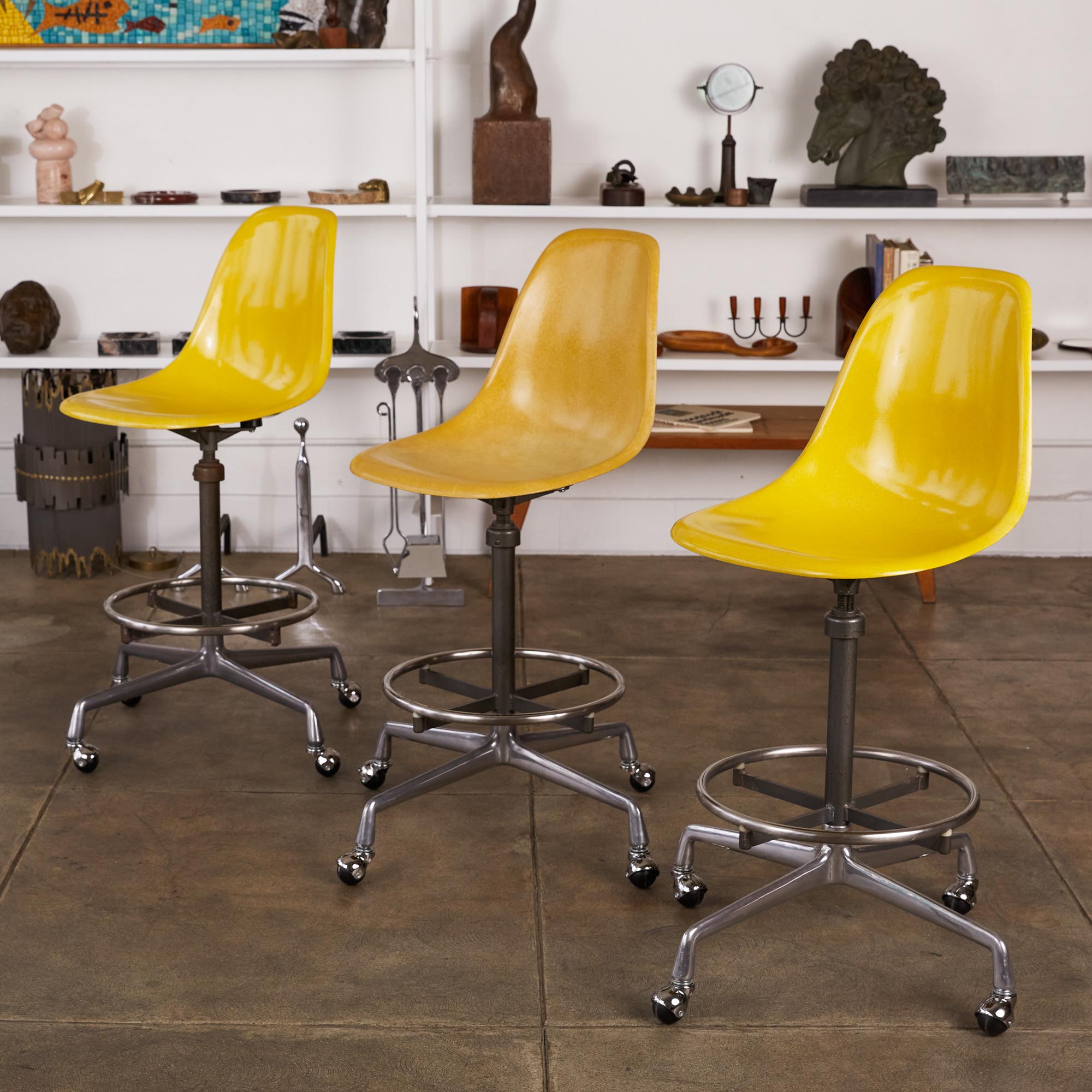 Set of three swiveling stools by Charles and Ray Eames for Herman Miller, circa 1975. The stools feature bright taxi cab yellow fiberglass shell seats that sit atop a height adjustable stem. The stools can be used for an office task chair or as a