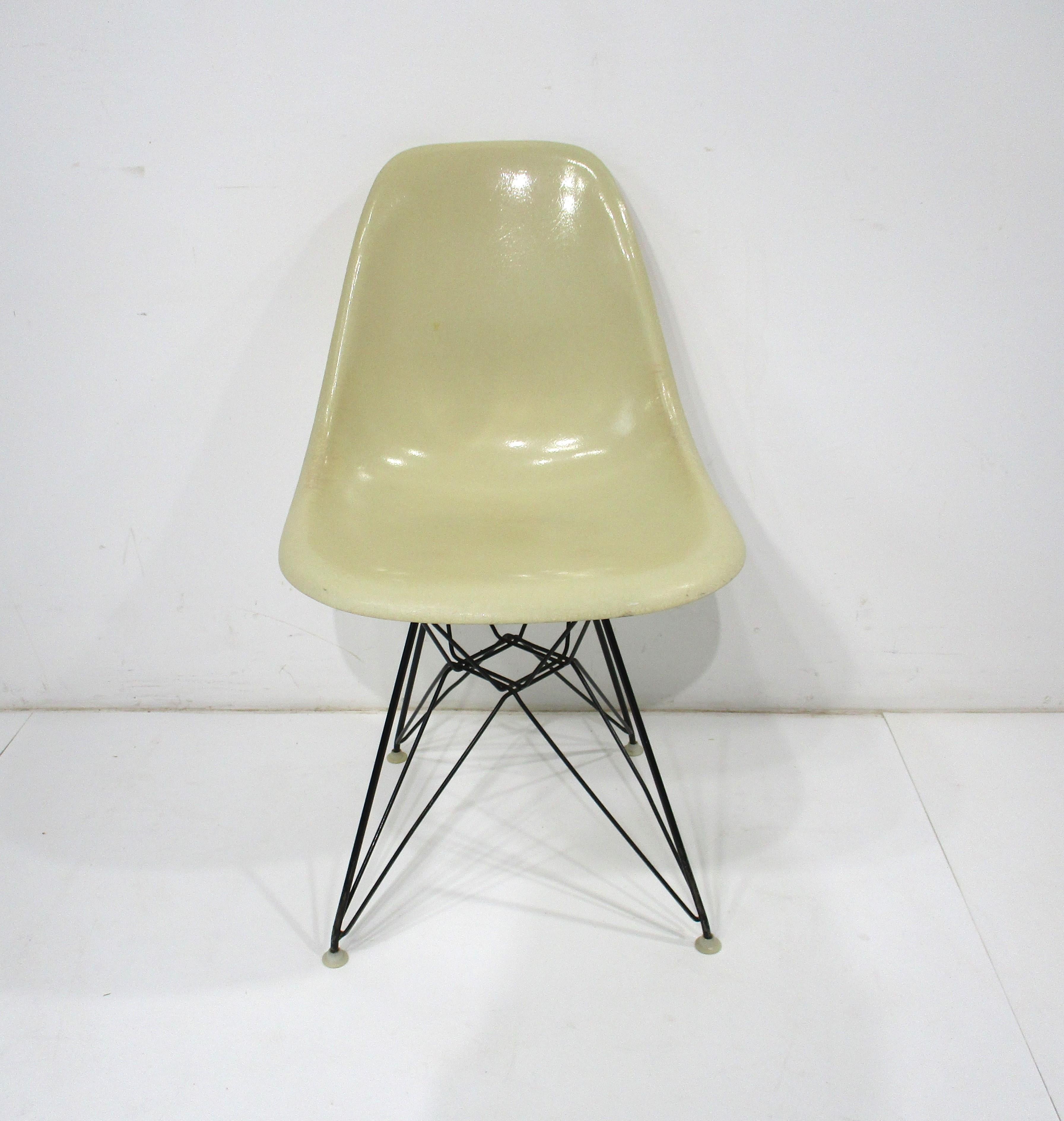 A parchment cream colored fiberglass desk chair with the satin black wire Eiffel tower base . The base has nylon foot pads to protect your floors and the slim and light look has great ergonomics for long periods of comfortable sitting . Designed by