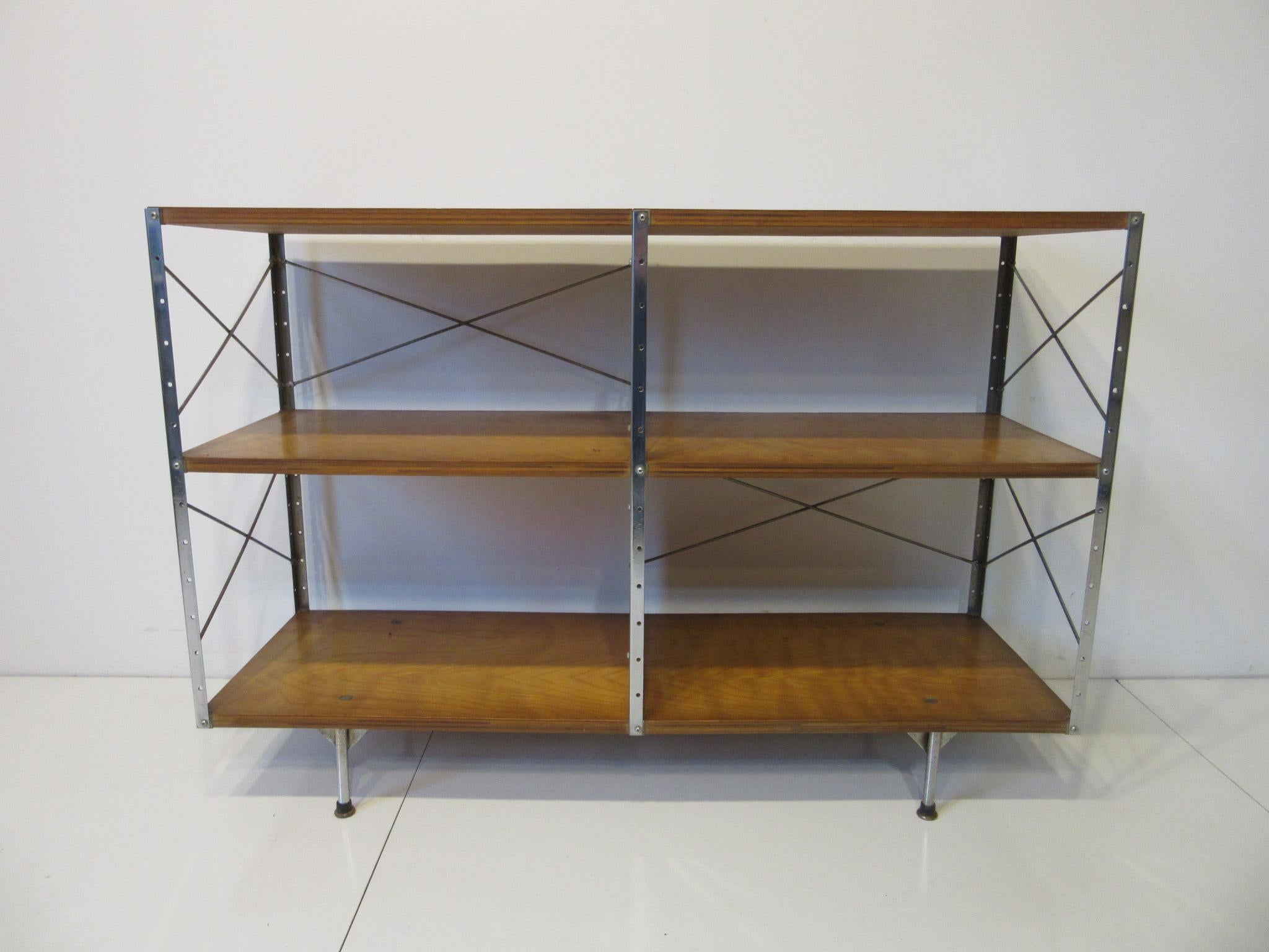 A vintage second series or generation Eames ESU 200- C storage unit with chrome coated steel L bracket frame and red divider panel. The top shelve is walnut ply while the two lower shelves are made of maple ply sitting on rounded legs marking it as