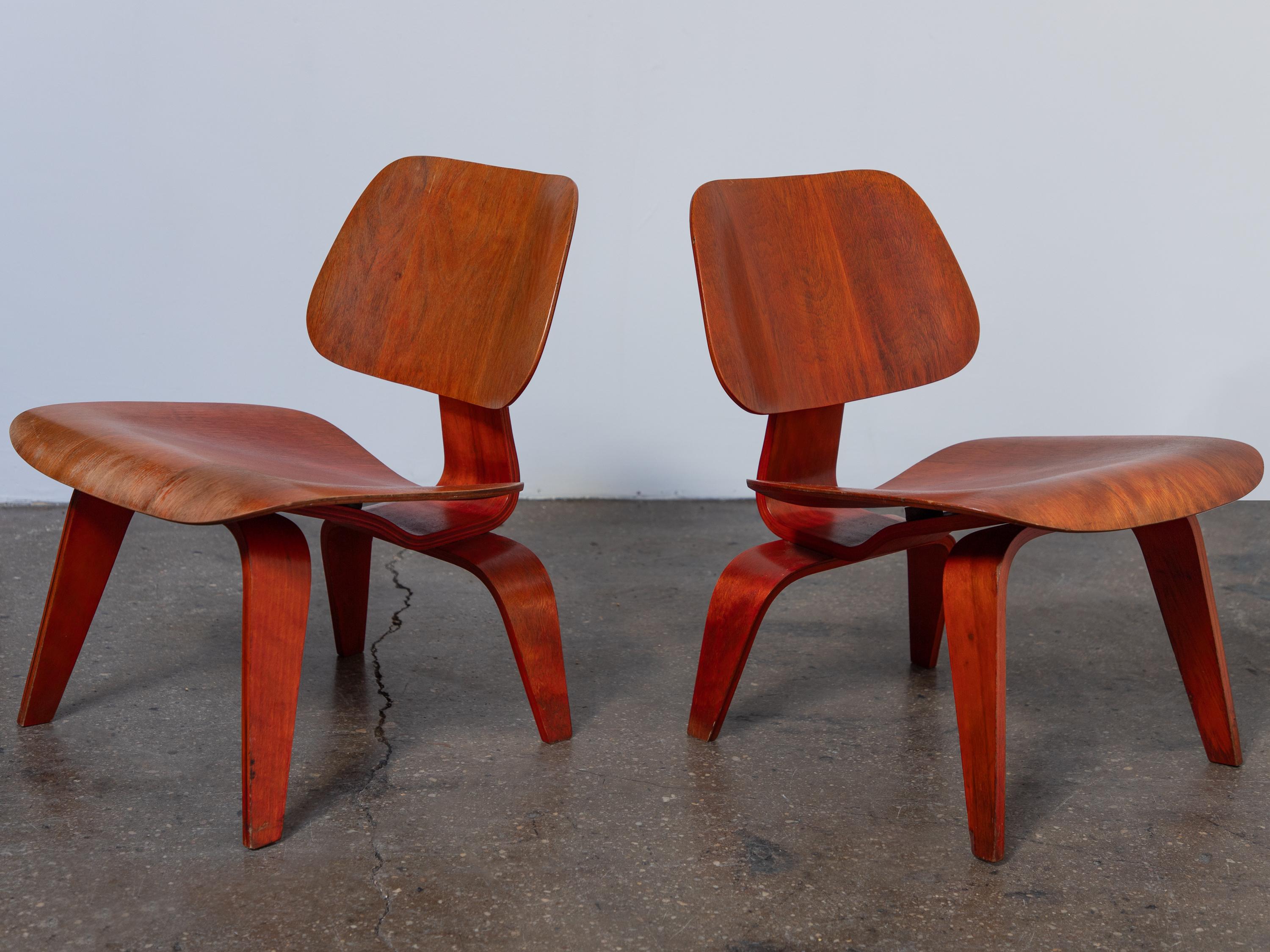 Spectacular matched set of red aniline dye LCW lounge chairs, designed by Charles and Ray Eames and manufactured by Evans Product Company (before Herman Miller production).  Aniline-dyed wood is vibrant and rich, showcasing the dramatic grain