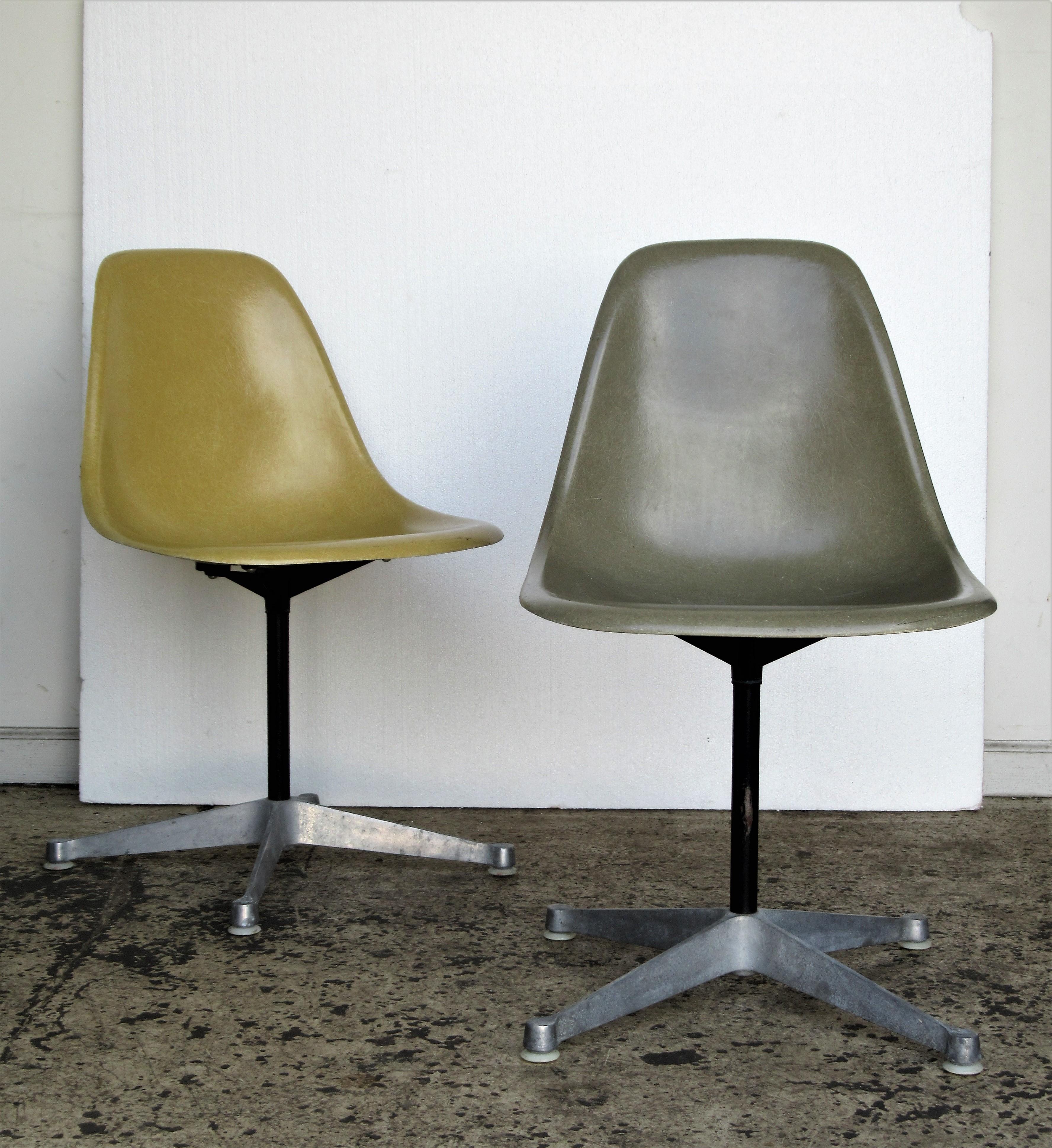 A pair of 100% all original 1960's Charles and Ray Eames fiberglass shell swivel chairs with four star aluminum bases. Both stamped with Herman Miller logo and Cincinnatti Milacron mark. One chair is light ochre yellow the other is the harder to