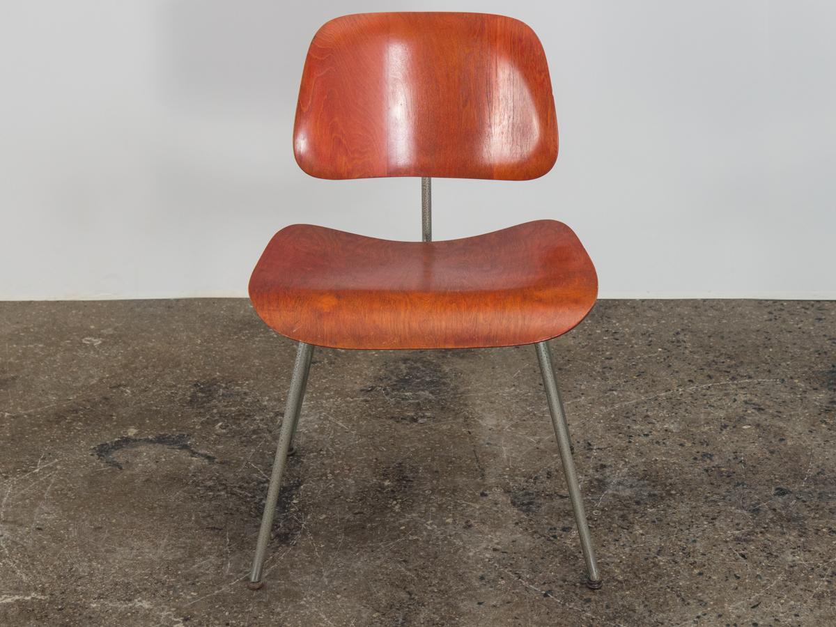 Scarce, early red aniline dye DCM dining chairs, designed by Charles and Ray Eames, made by Evans for Herman Miller. Molded plywood has great age, wearing its original patina handsomely. Original finish is unaltered. In excellent shape, with very