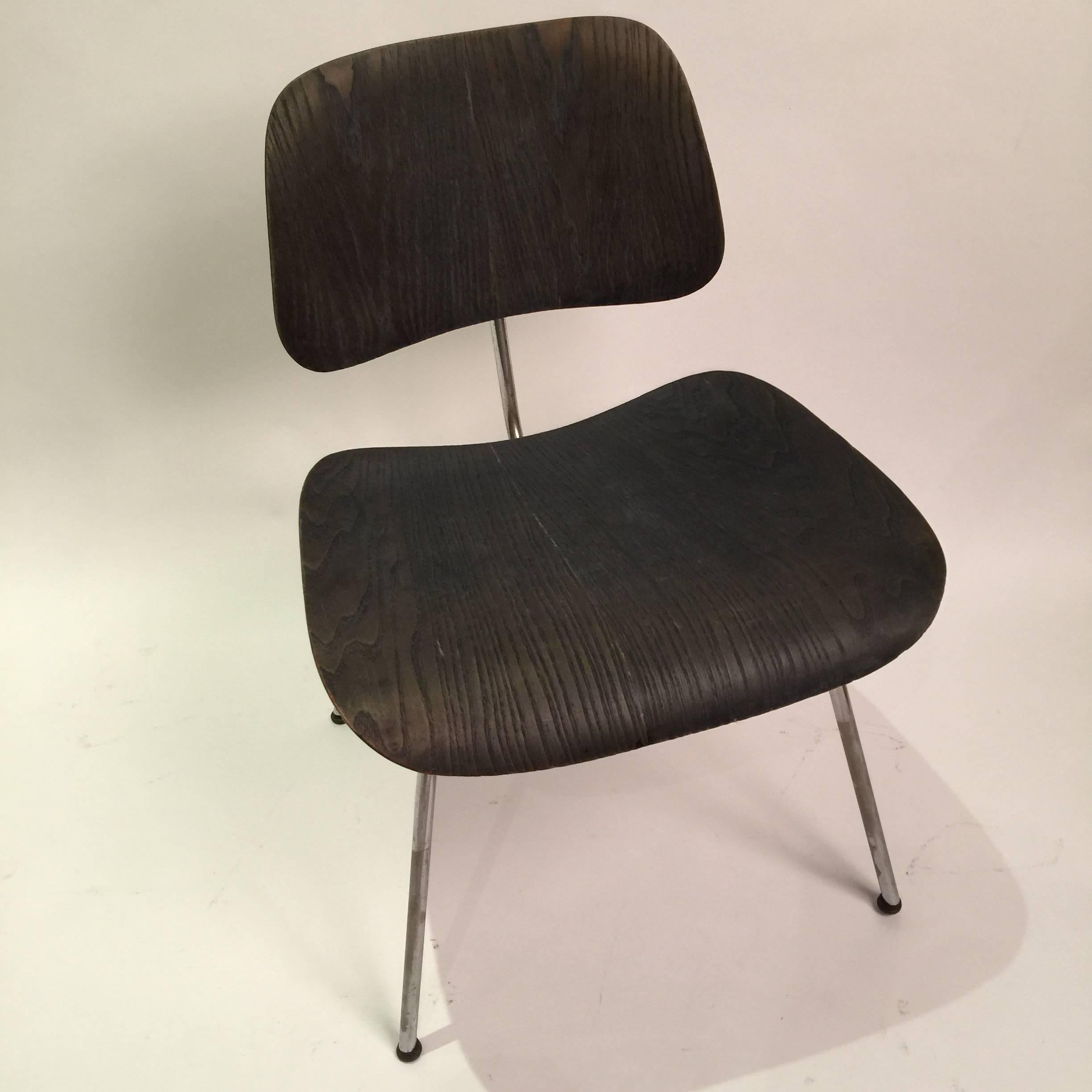 Black aniline DCM dining chairs by Charles and Ray Eames. These first edition chairs were produced by Evans manufacturing and distributed by Herman Miller. Chair has labels intact and original domes of silence glides. Excellent patina.