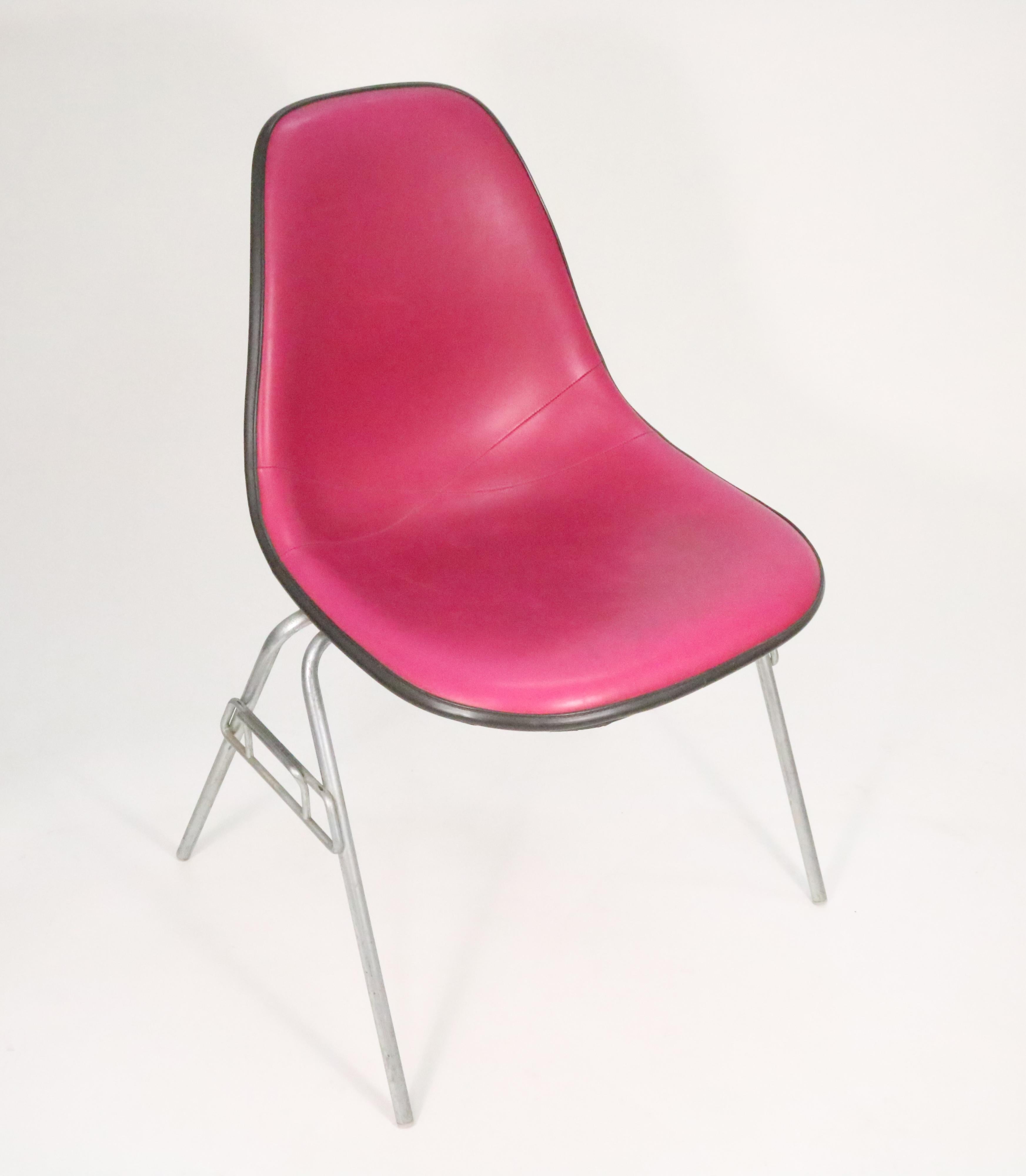 An eye-catching edition of Charles and Ray Eames' molded fiberglass side chair upholstered in bright pink vinyl with original DSS stackable cast aluminum base.